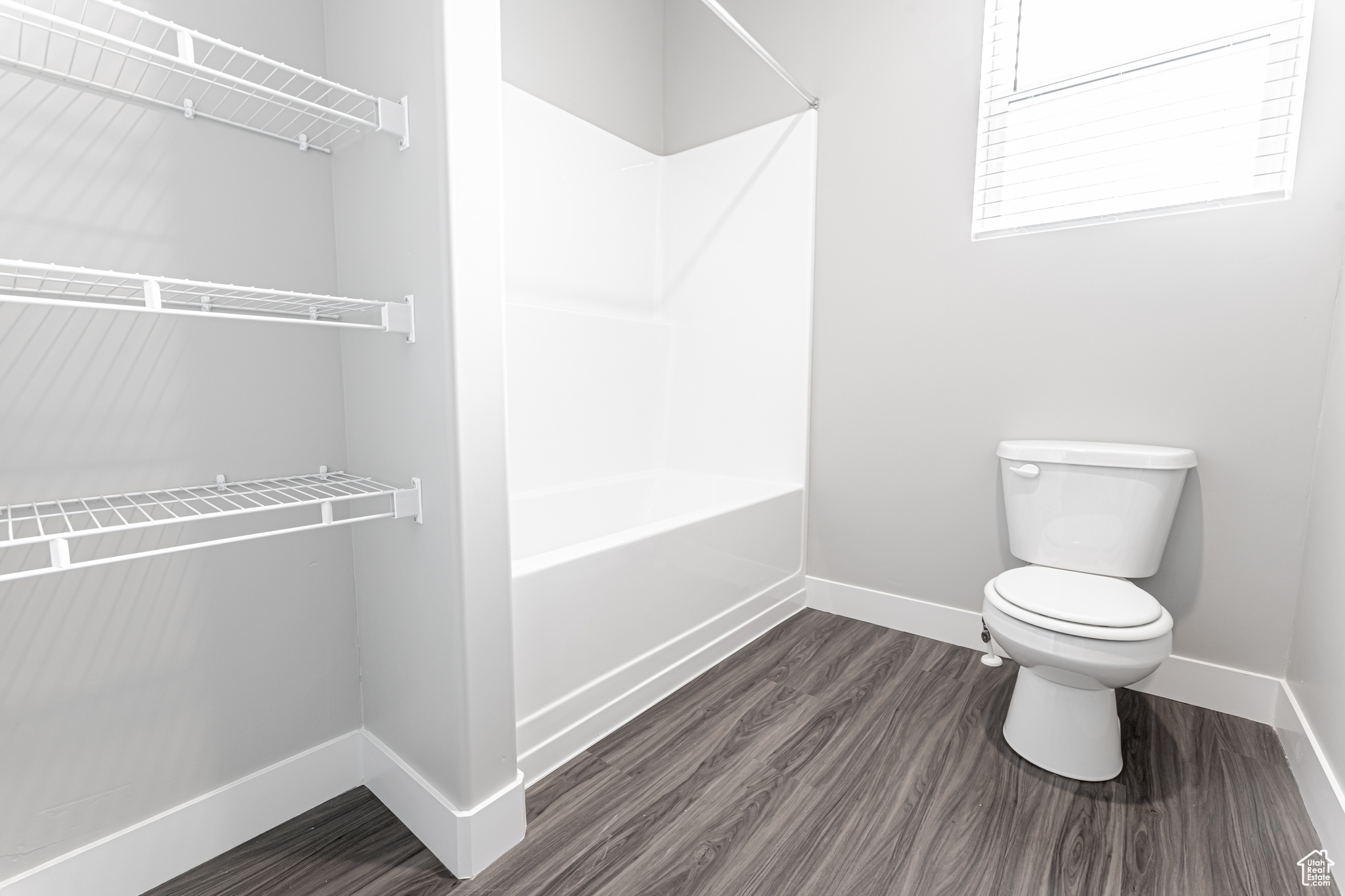 Bathroom with toilet, washtub / shower combination, and hardwood / wood-style floors