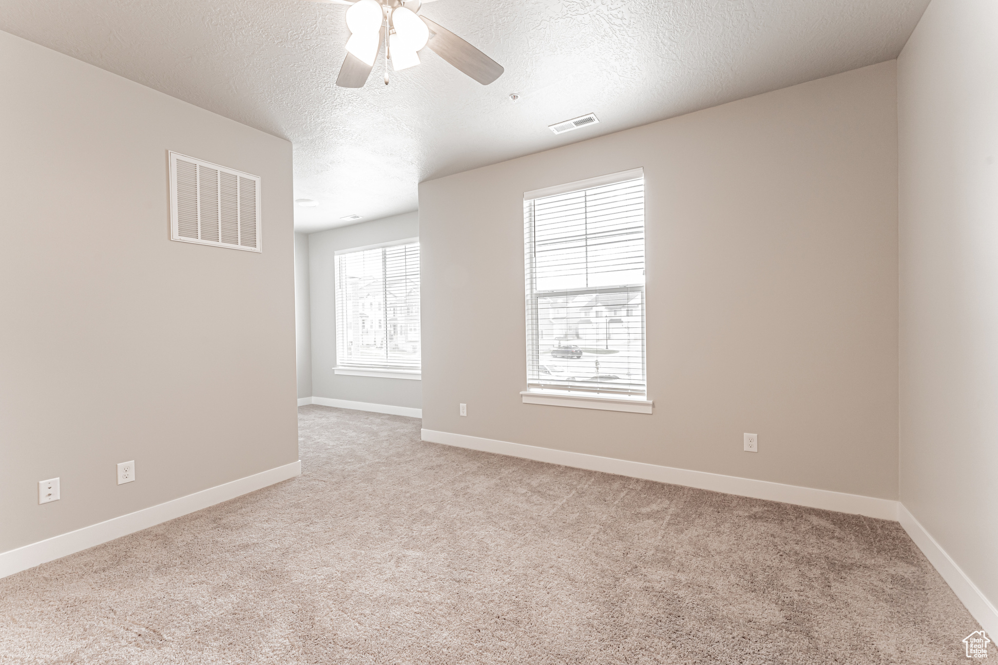 Carpeted empty room featuring a textured ceiling and ceiling fan