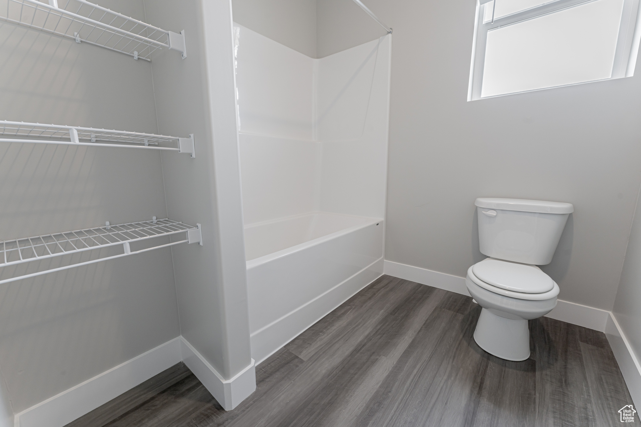 Bathroom featuring toilet, tub / shower combination, and wood-type flooring