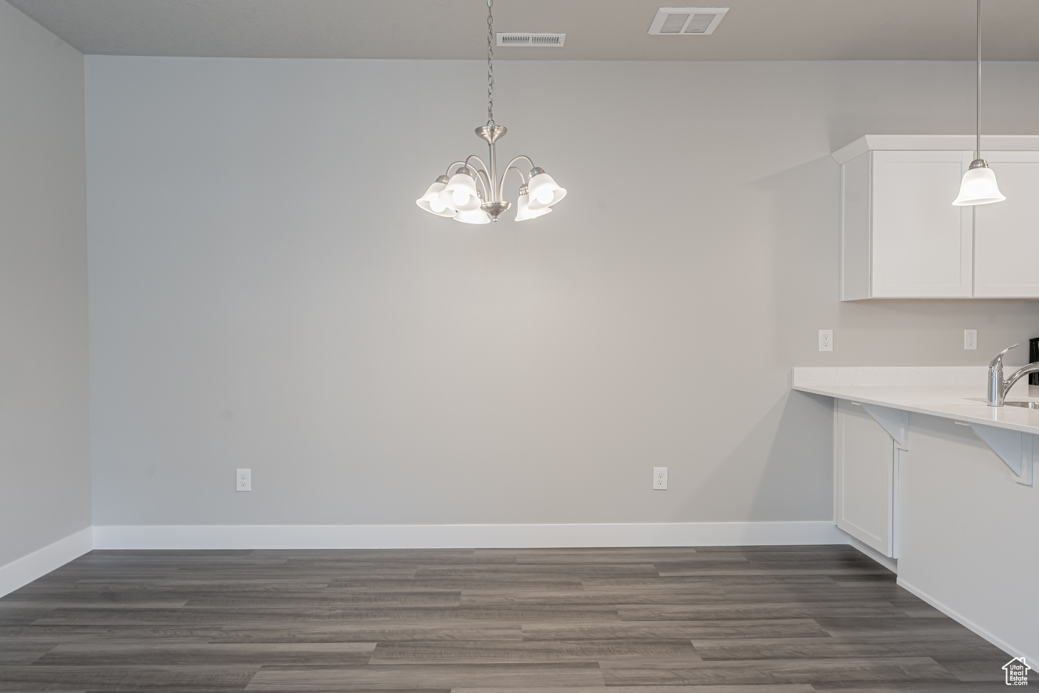 Unfurnished dining area featuring sink, a notable chandelier, and dark wood-type flooring