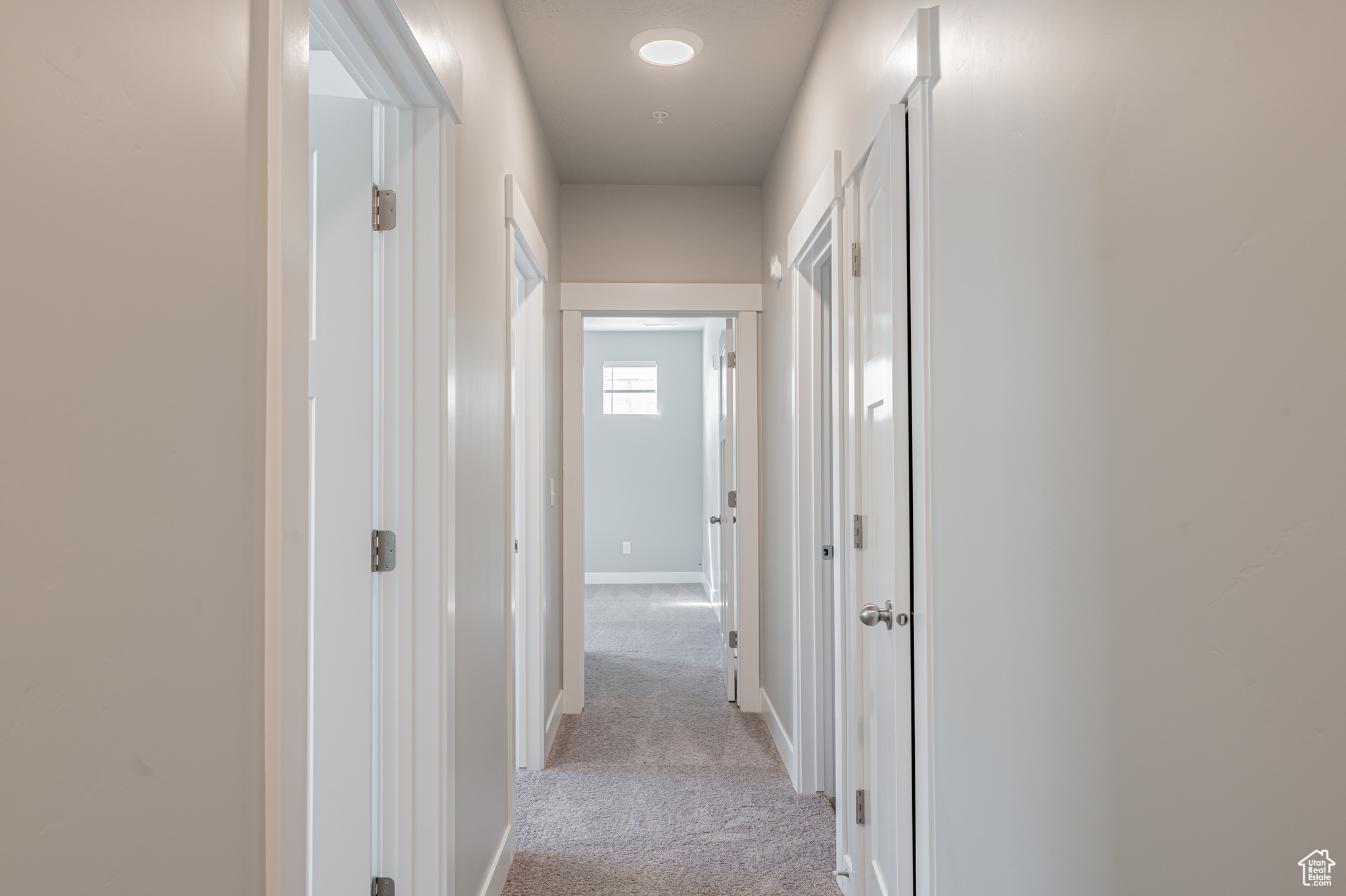 Corridor featuring light colored carpet