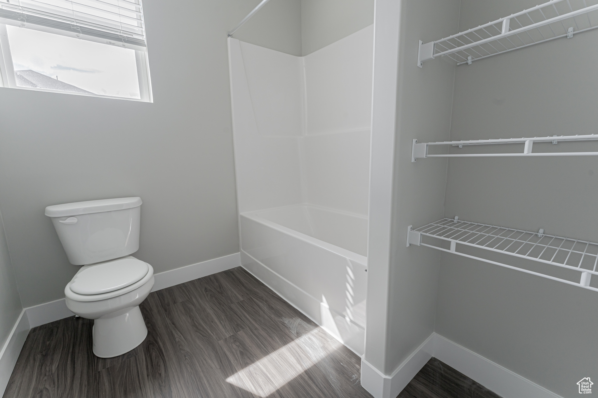 Bathroom with bathing tub / shower combination, wood-type flooring, and toilet