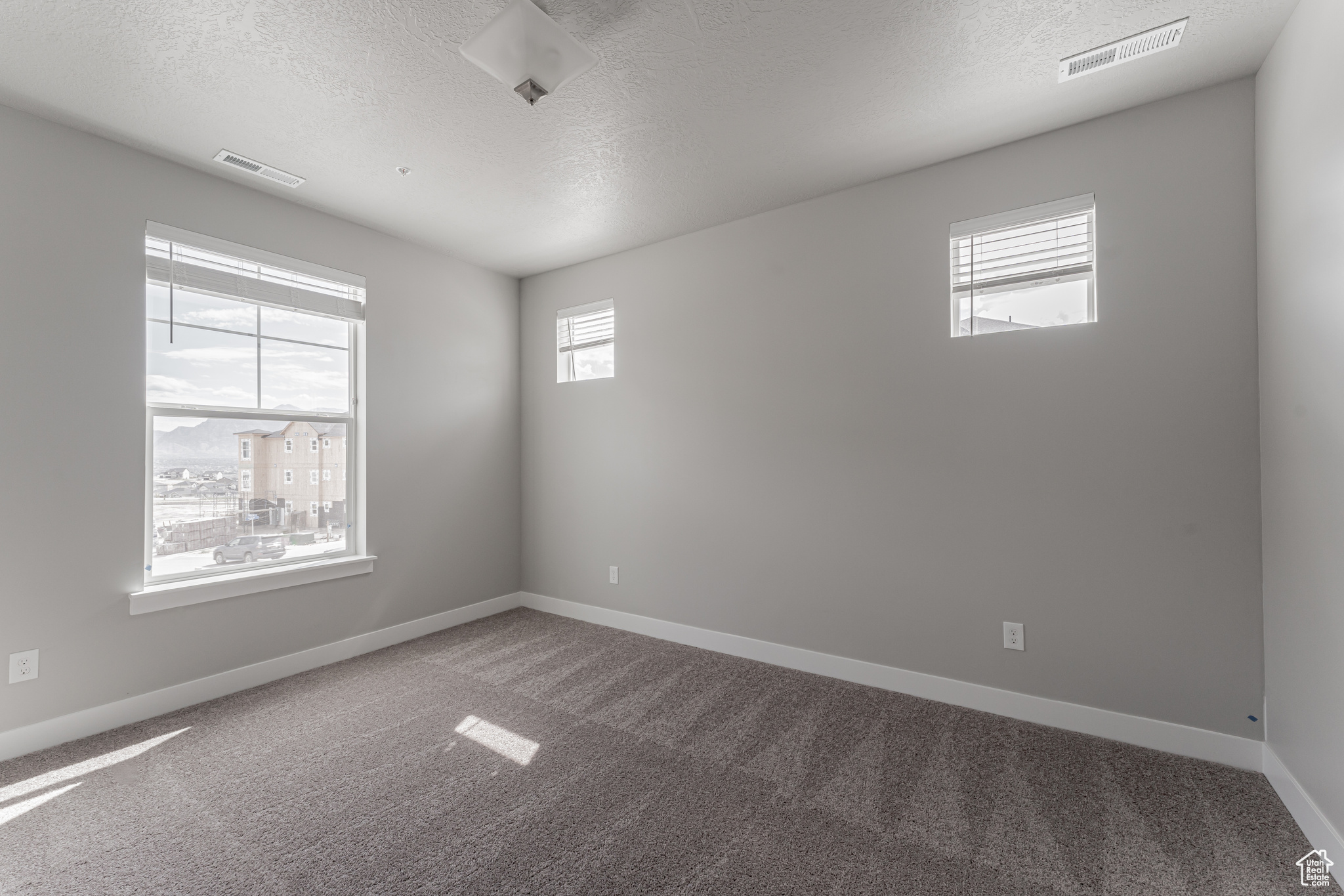 Carpeted spare room with a textured ceiling