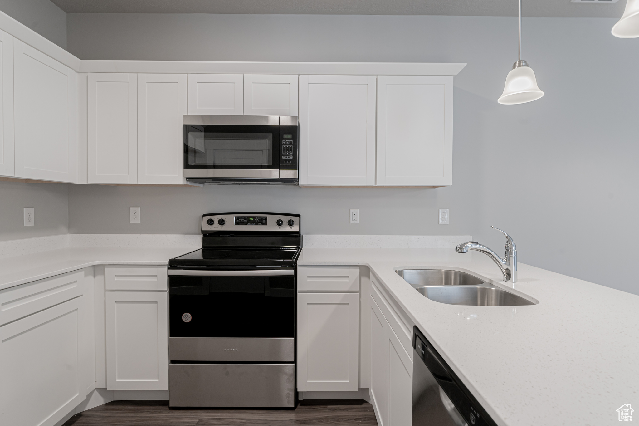 Kitchen featuring appliances with stainless steel finishes, dark wood-type flooring, white cabinetry, and sink