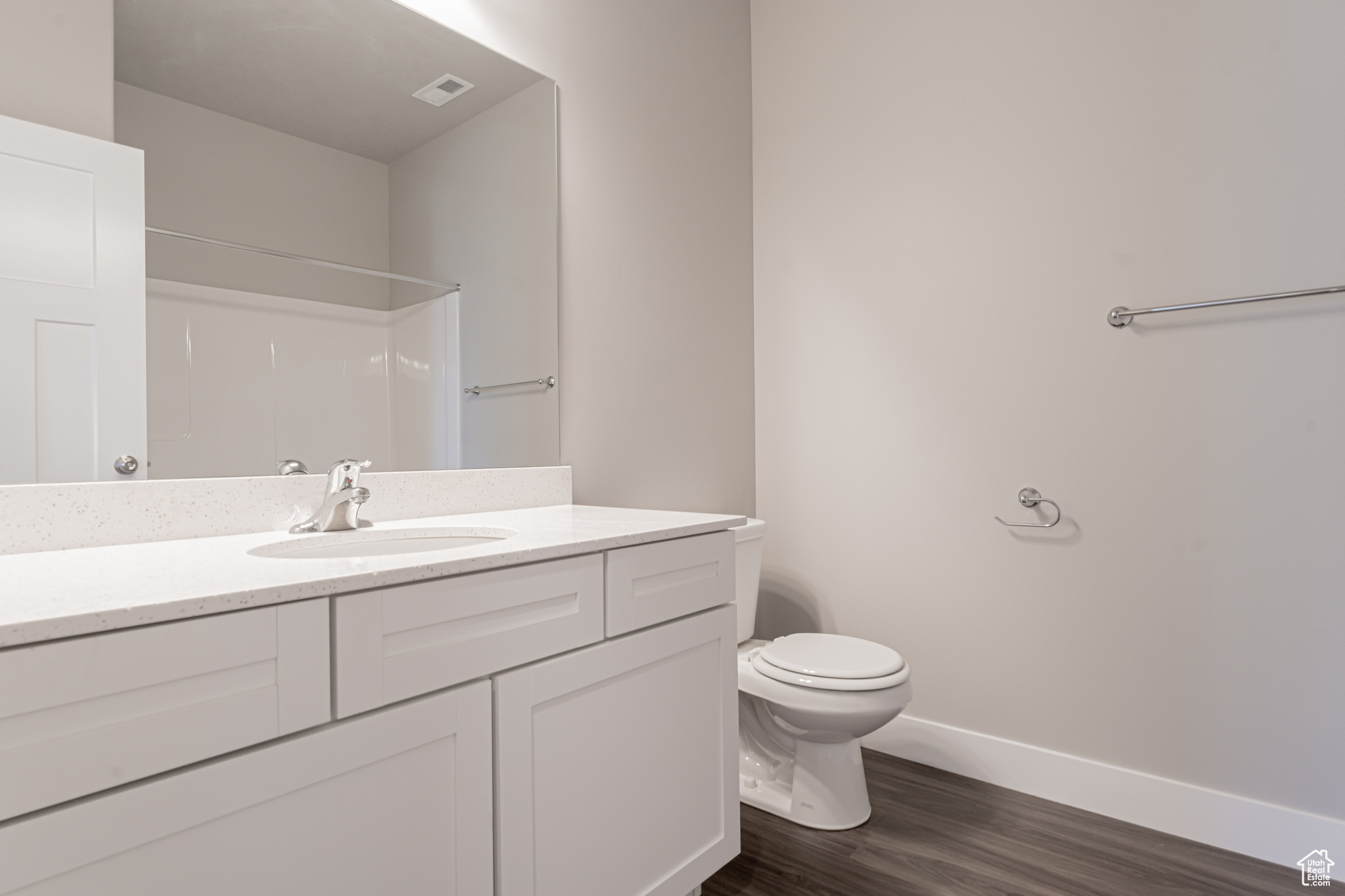 Bathroom with hardwood / wood-style flooring, vanity, walk in shower, and toilet