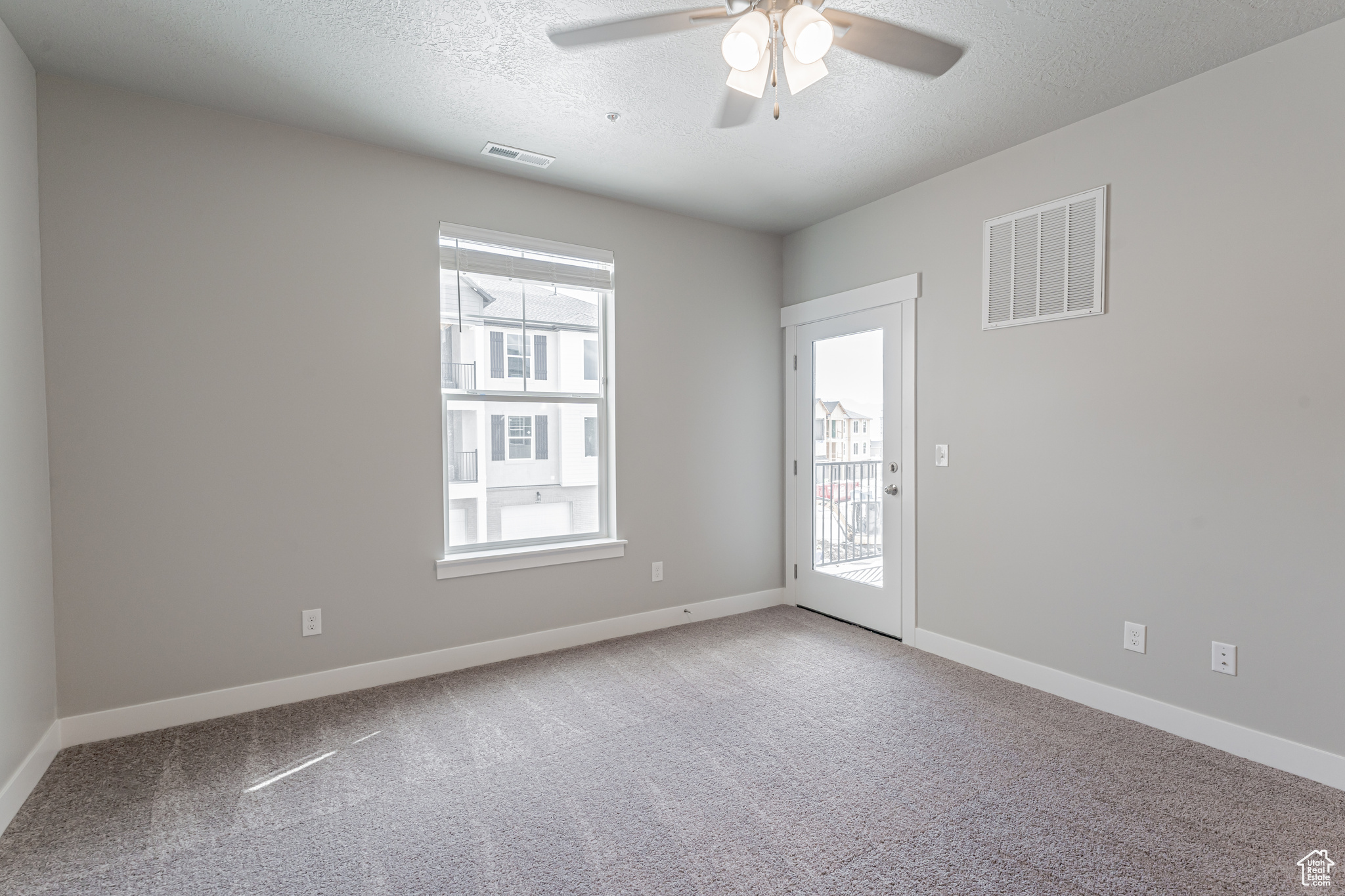 Carpeted empty room with a textured ceiling and ceiling fan