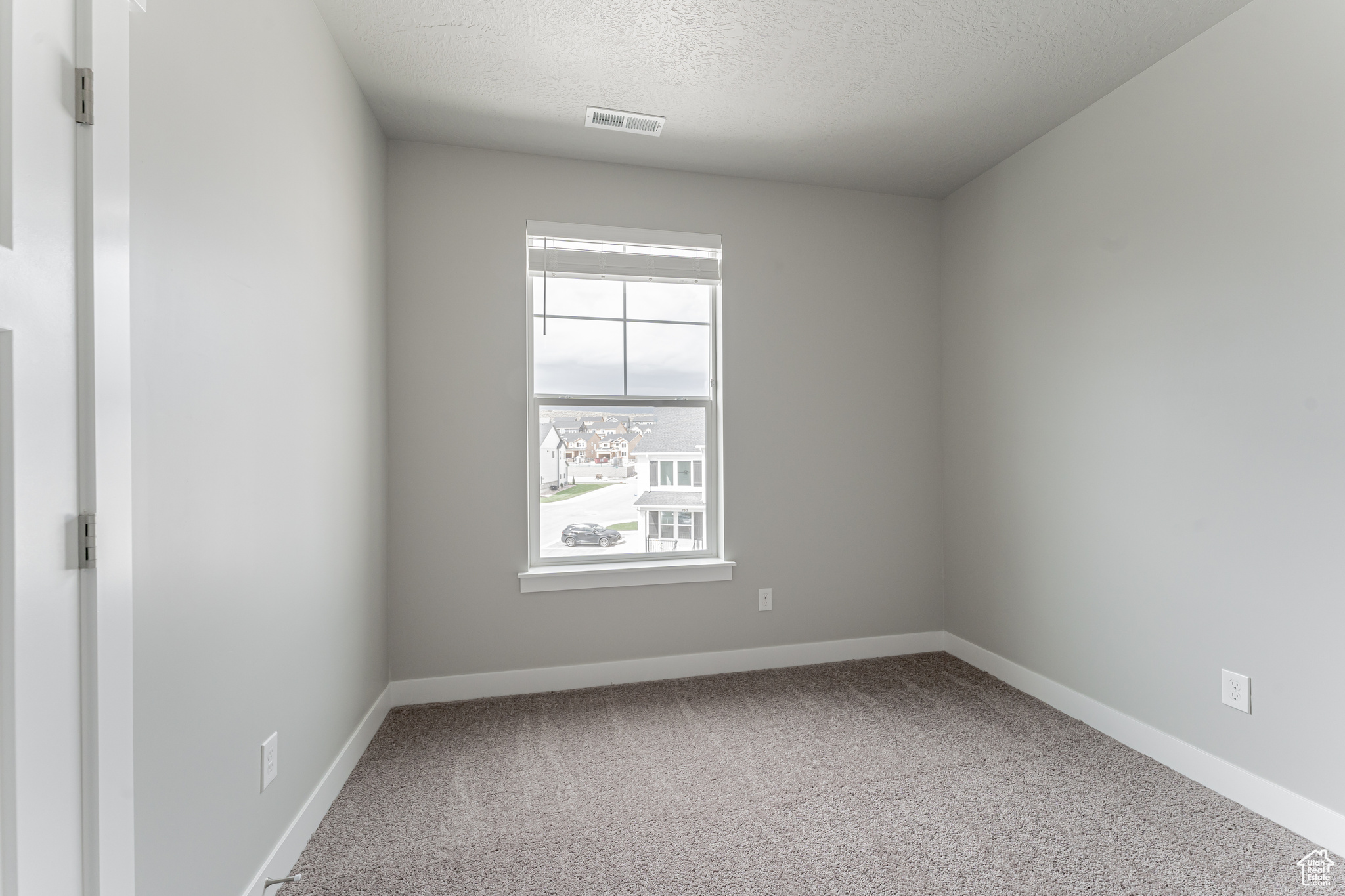 Carpeted empty room with a textured ceiling