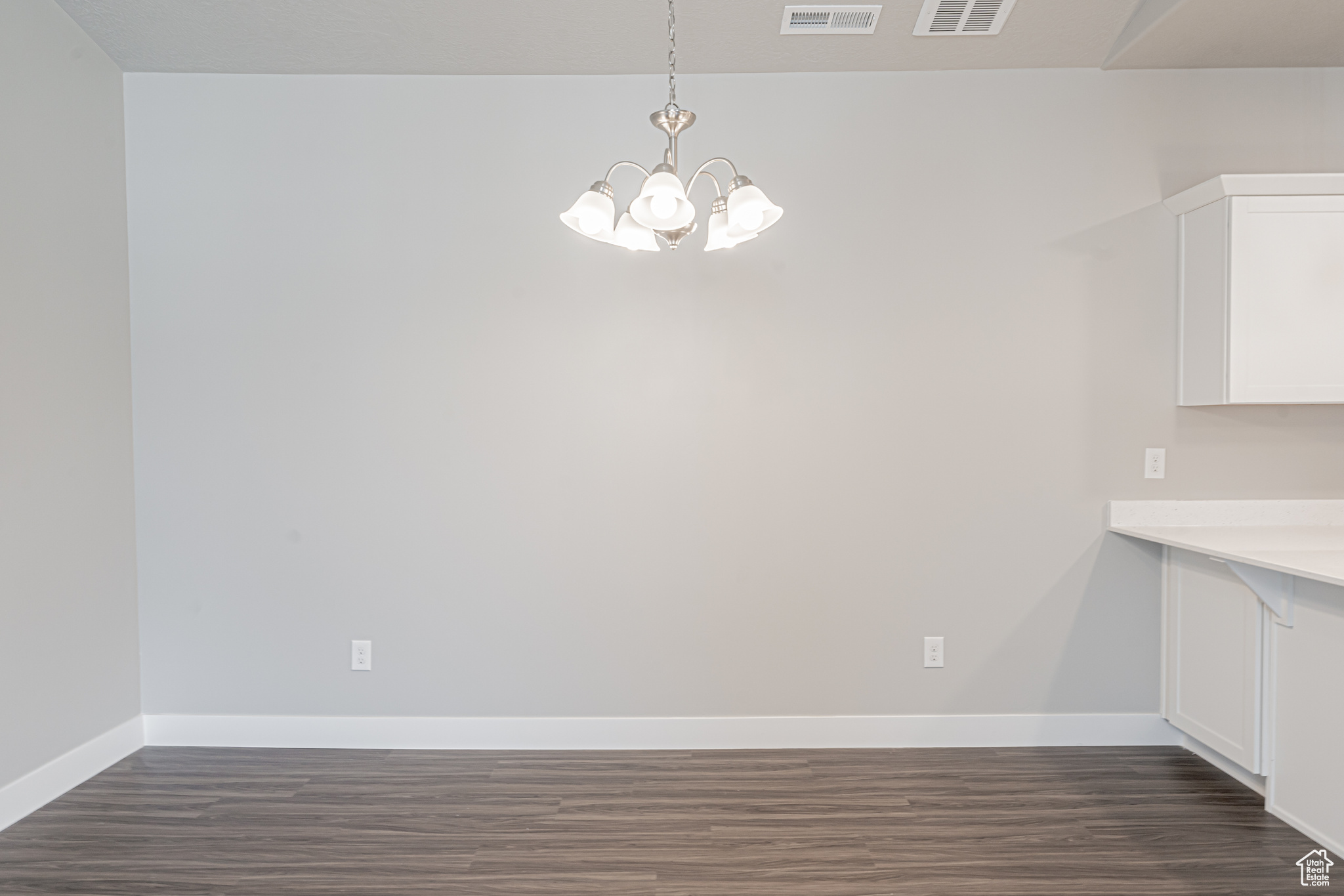 Unfurnished dining area with dark wood-type flooring and a chandelier