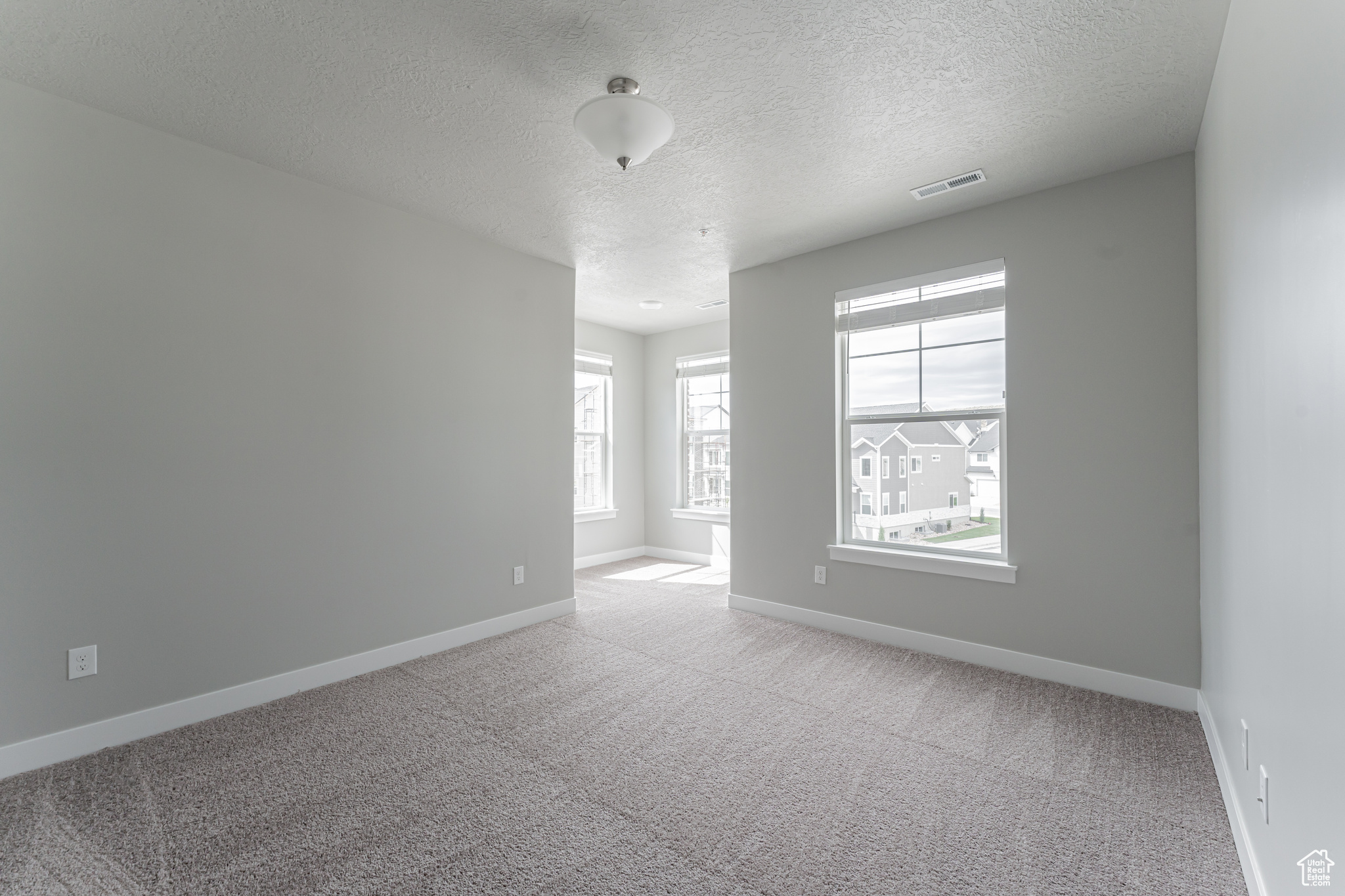 Spare room featuring light carpet and a textured ceiling