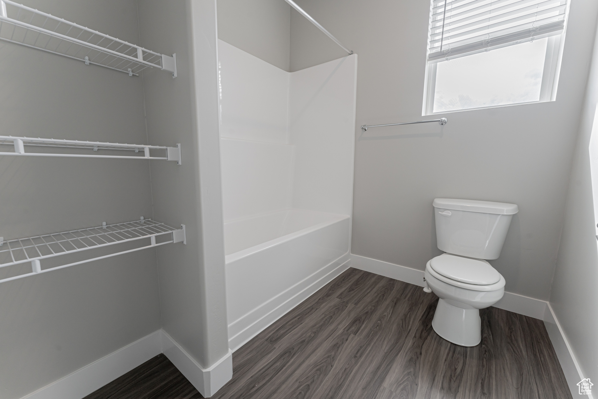 Bathroom featuring bathtub / shower combination, wood-type flooring, and toilet