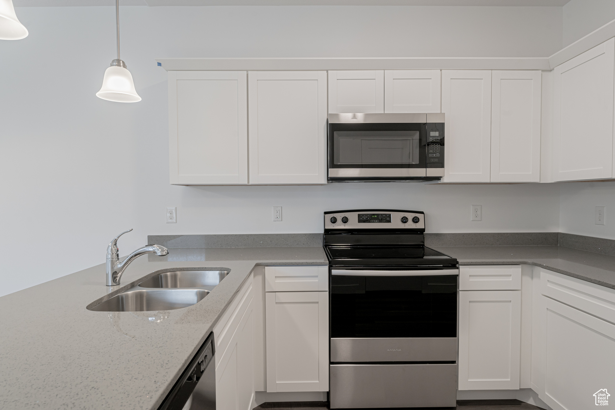 Kitchen featuring sink, white cabinetry, pendant lighting, and stainless steel appliances