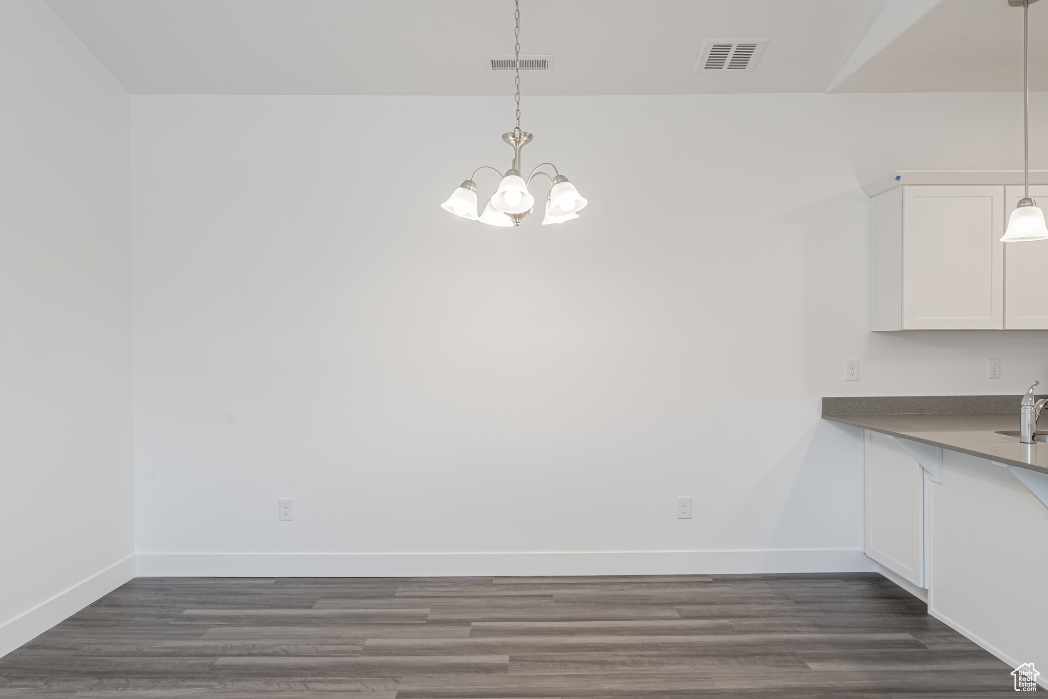 Unfurnished dining area with sink, a notable chandelier, and dark hardwood / wood-style floors