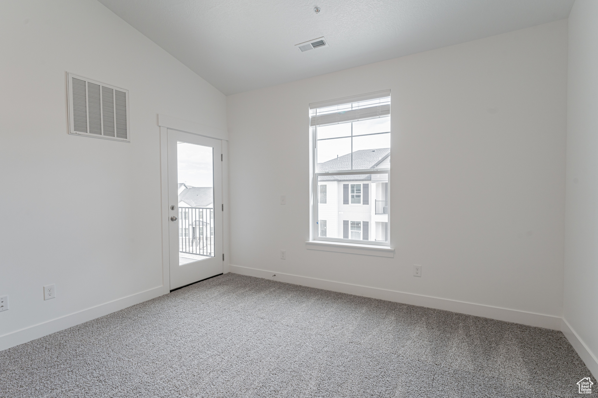 Carpeted empty room with vaulted ceiling