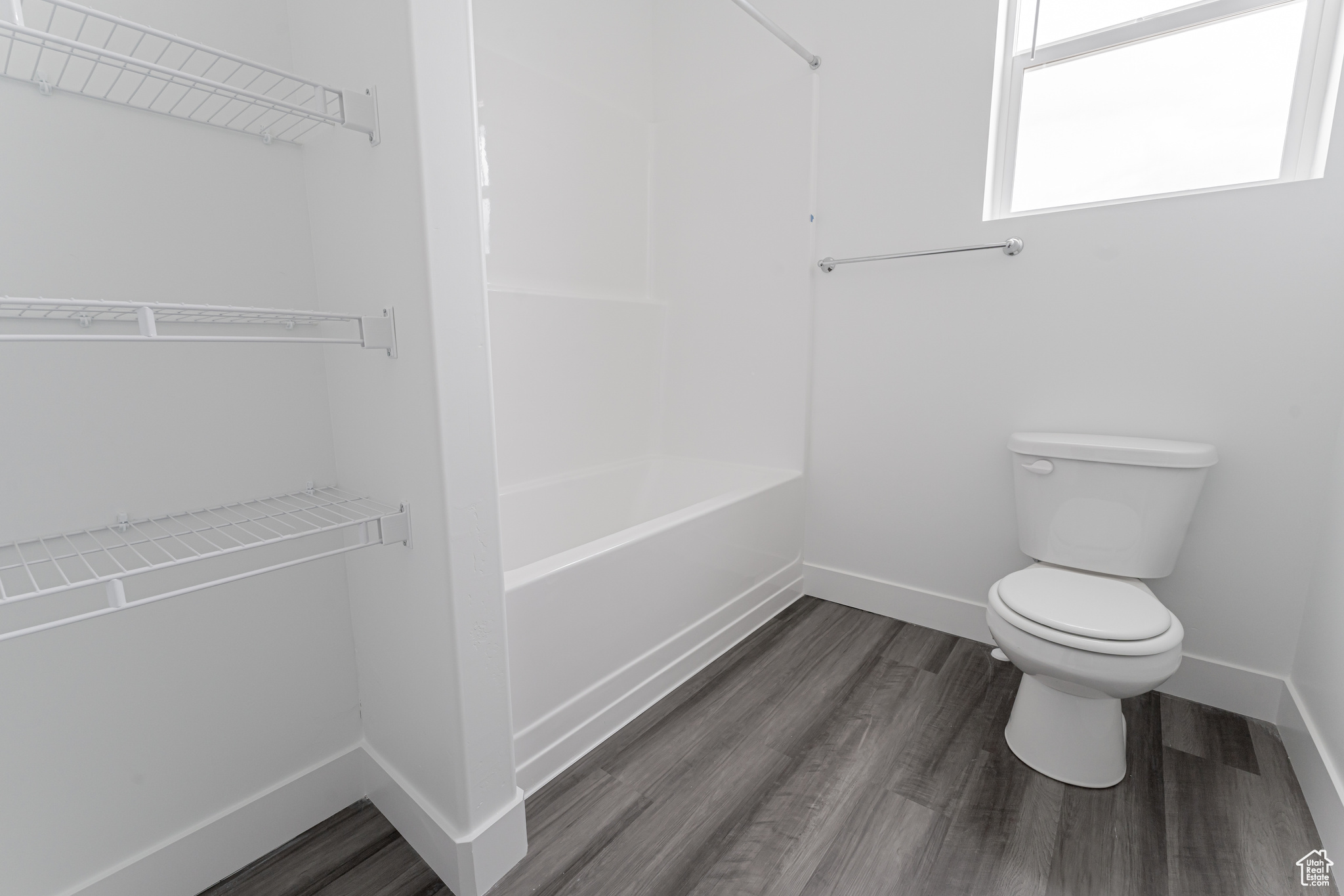 Bathroom featuring hardwood / wood-style flooring, shower / washtub combination, and toilet