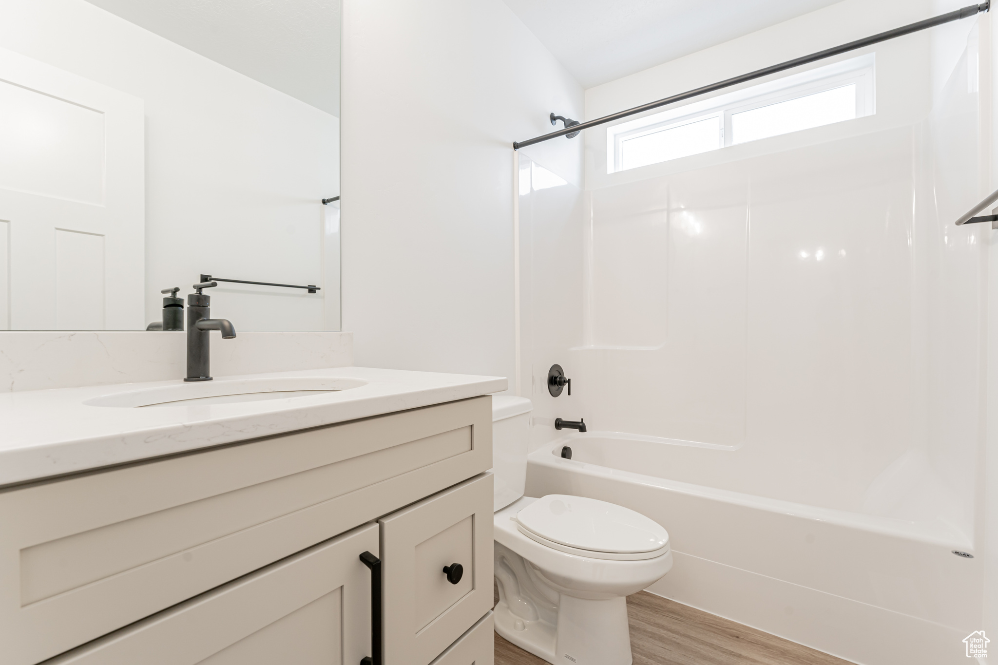 Full bathroom with vanity, hardwood / wood-style floors, shower / tub combination, and toilet