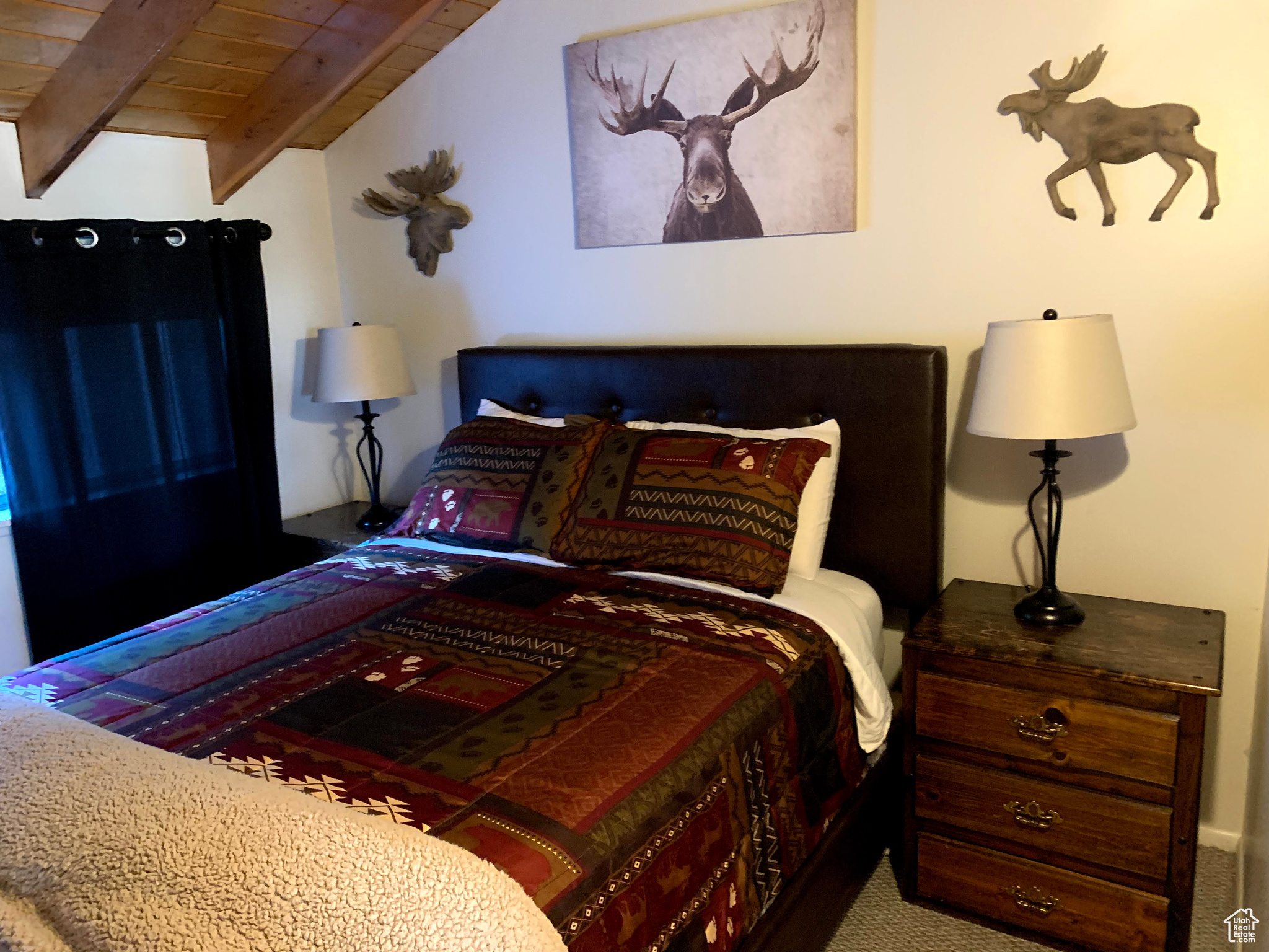 Carpeted bedroom with vaulted ceiling with beams and wood ceiling