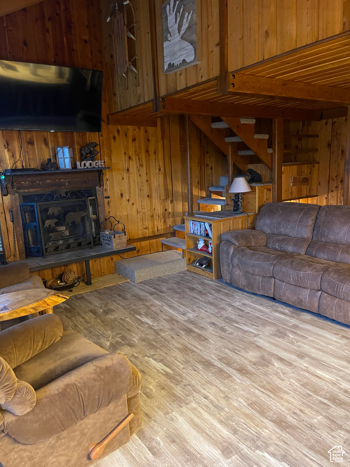 Living room with light hardwood / wood-style flooring and wood walls