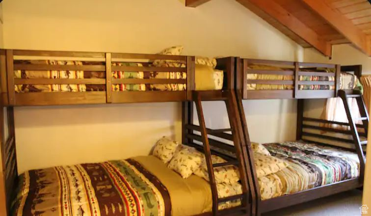 Carpeted bedroom with lofted ceiling with beams