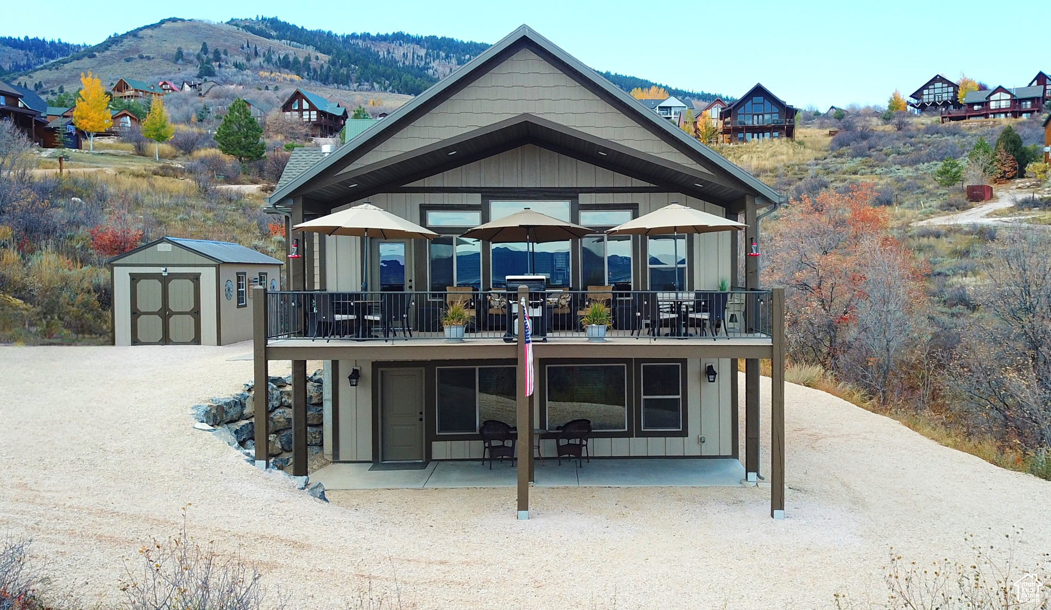 Front view of property featuring a mountain view, a balcony, a patio area, and a storage shed