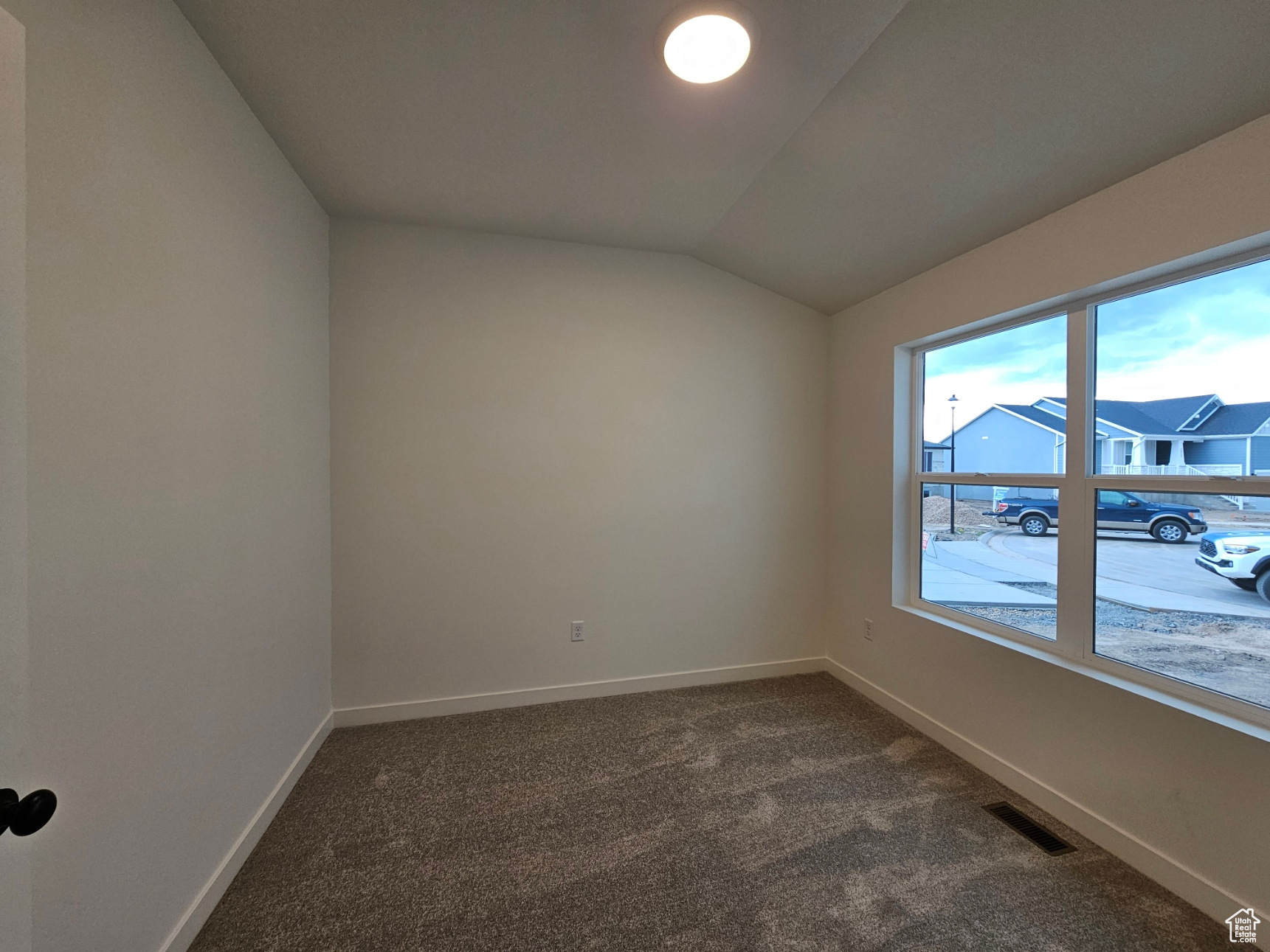 Empty room featuring carpet floors and lofted ceiling