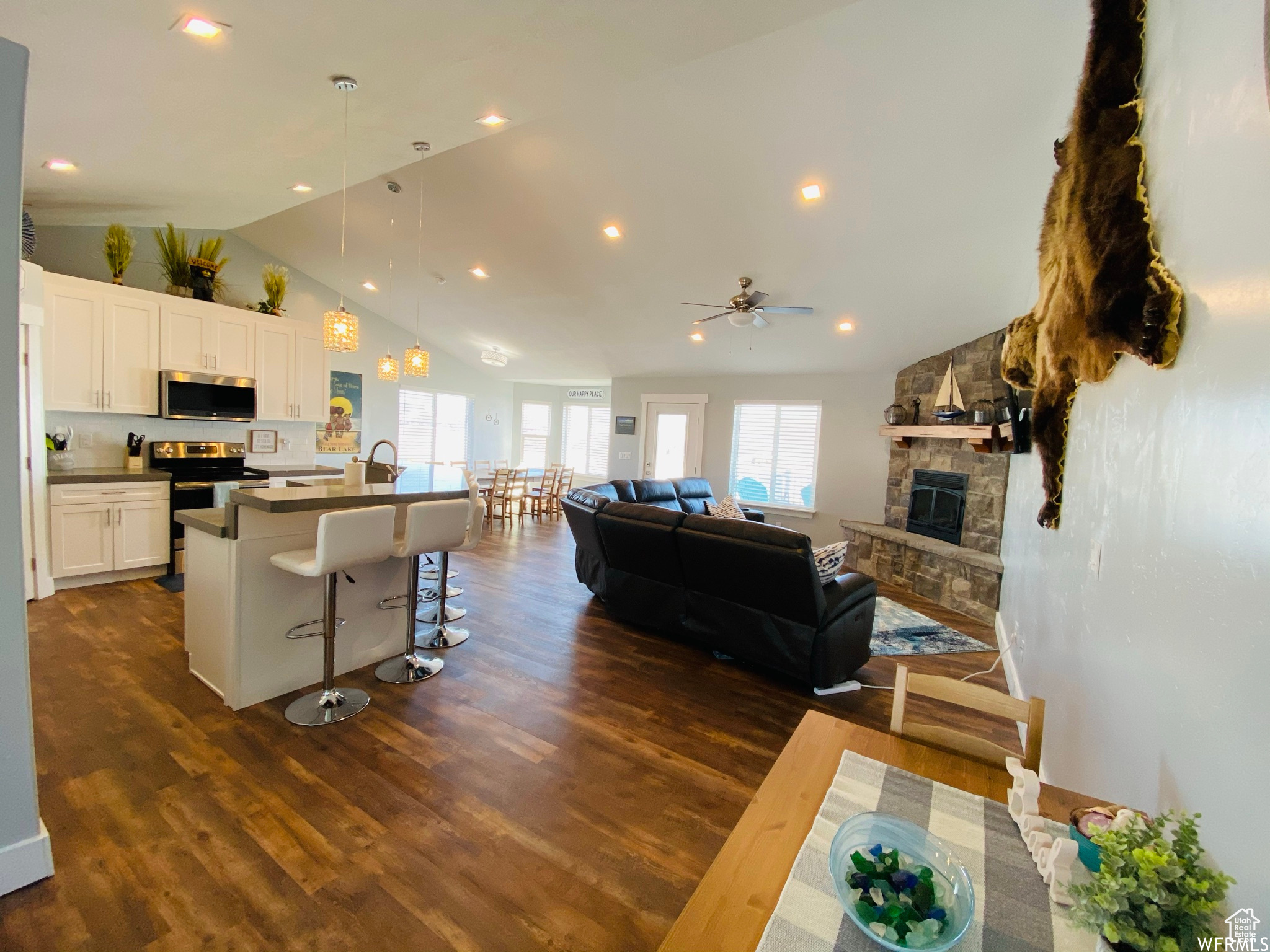 Dining area featuring ceiling fan, a fireplace, dark hardwood / wood-style floors, sink, and lofted ceiling