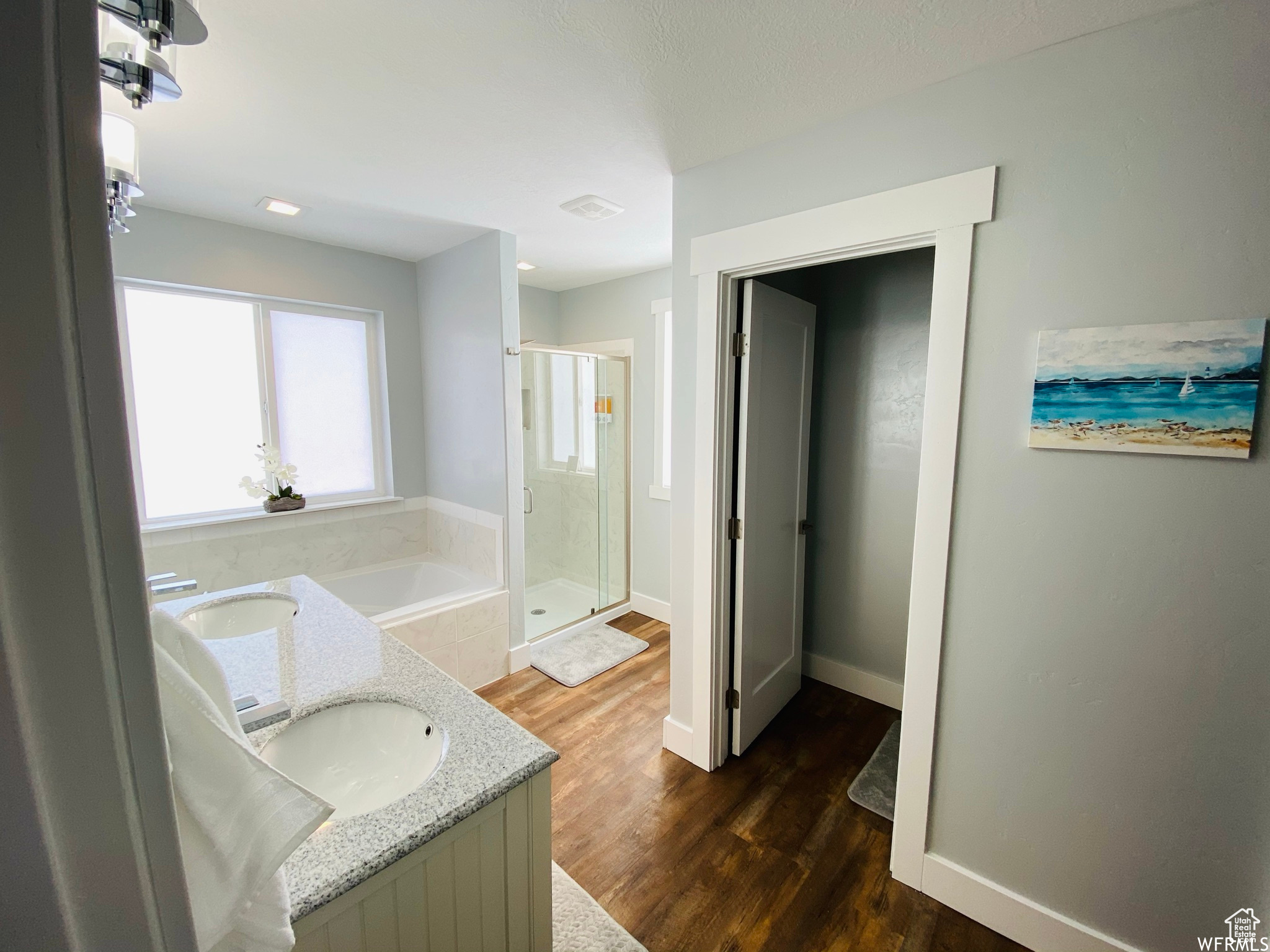 Bathroom featuring independent shower and bath, double sink vanity, and hardwood / wood-style floors