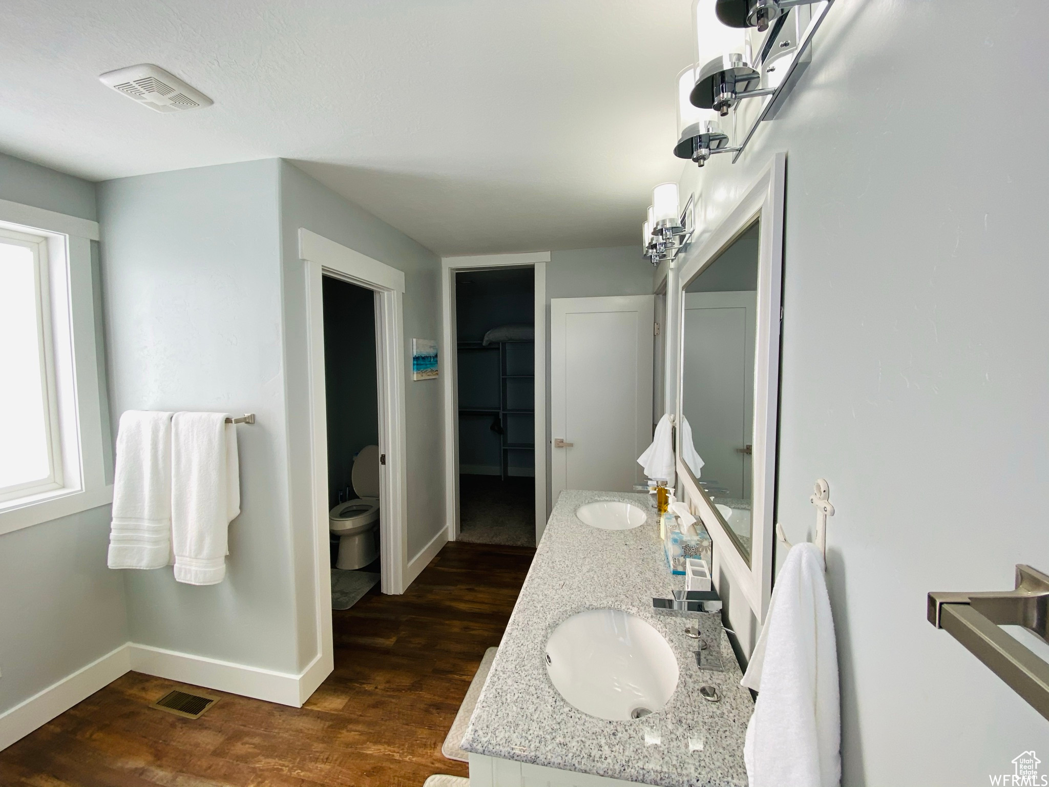 Bathroom with dual bowl vanity, hardwood / wood-style floors, and toilet