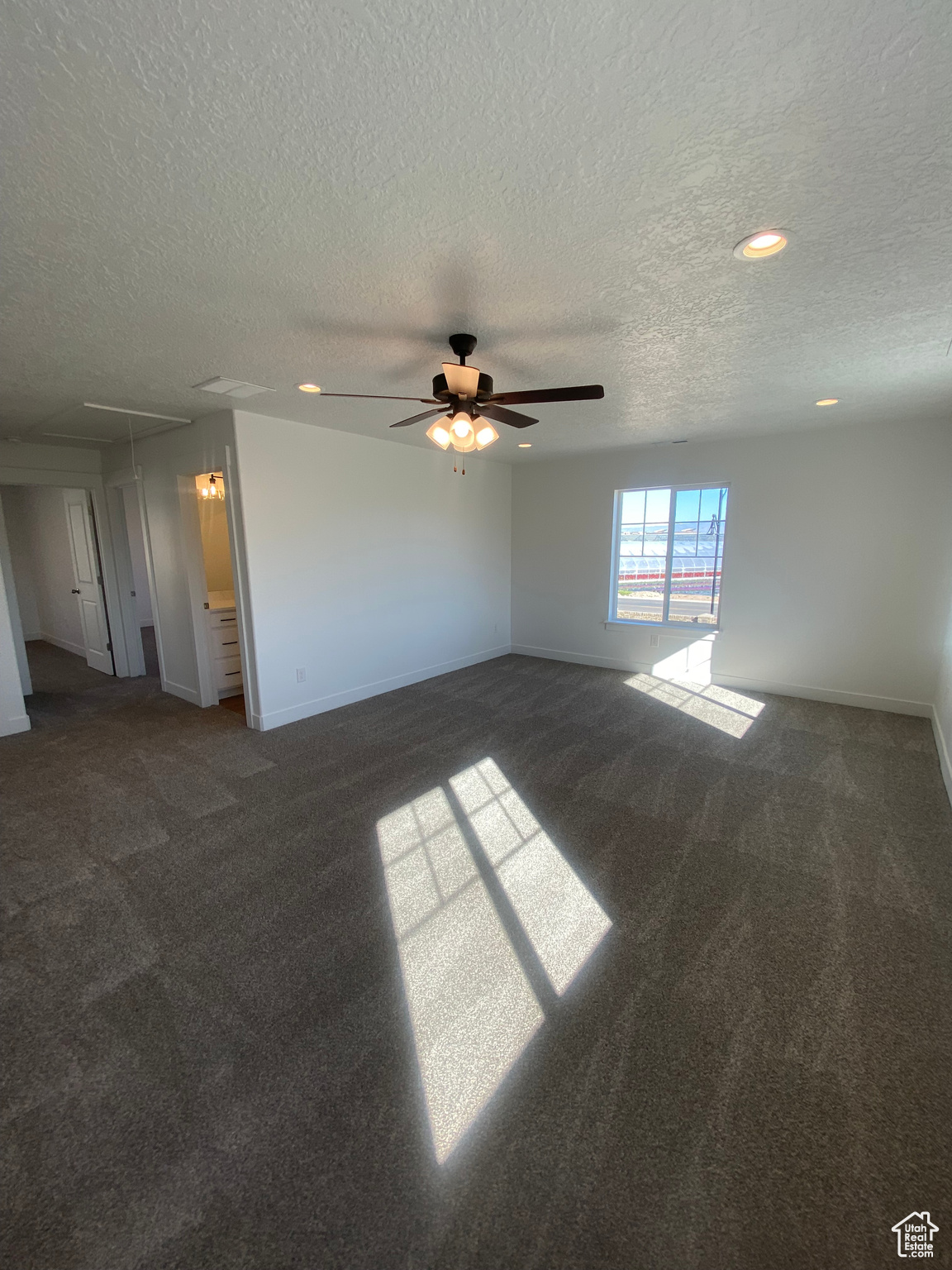 Empty room with ceiling fan, a textured ceiling, and dark carpet. Pictures are for reference only of the MAINE floor plan. Actual finishes may vary.