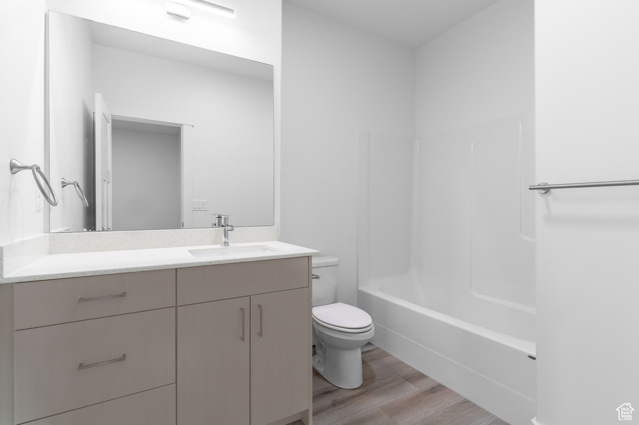 Full bathroom featuring hardwood / wood-style flooring, bathtub / shower combination, vanity, and toilet
