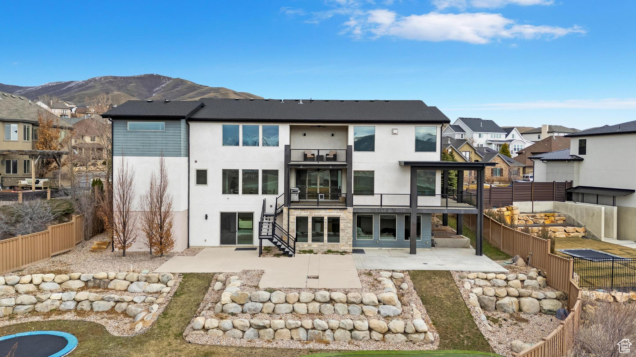 Rear view of property with a mountain view, a balcony, and a patio area