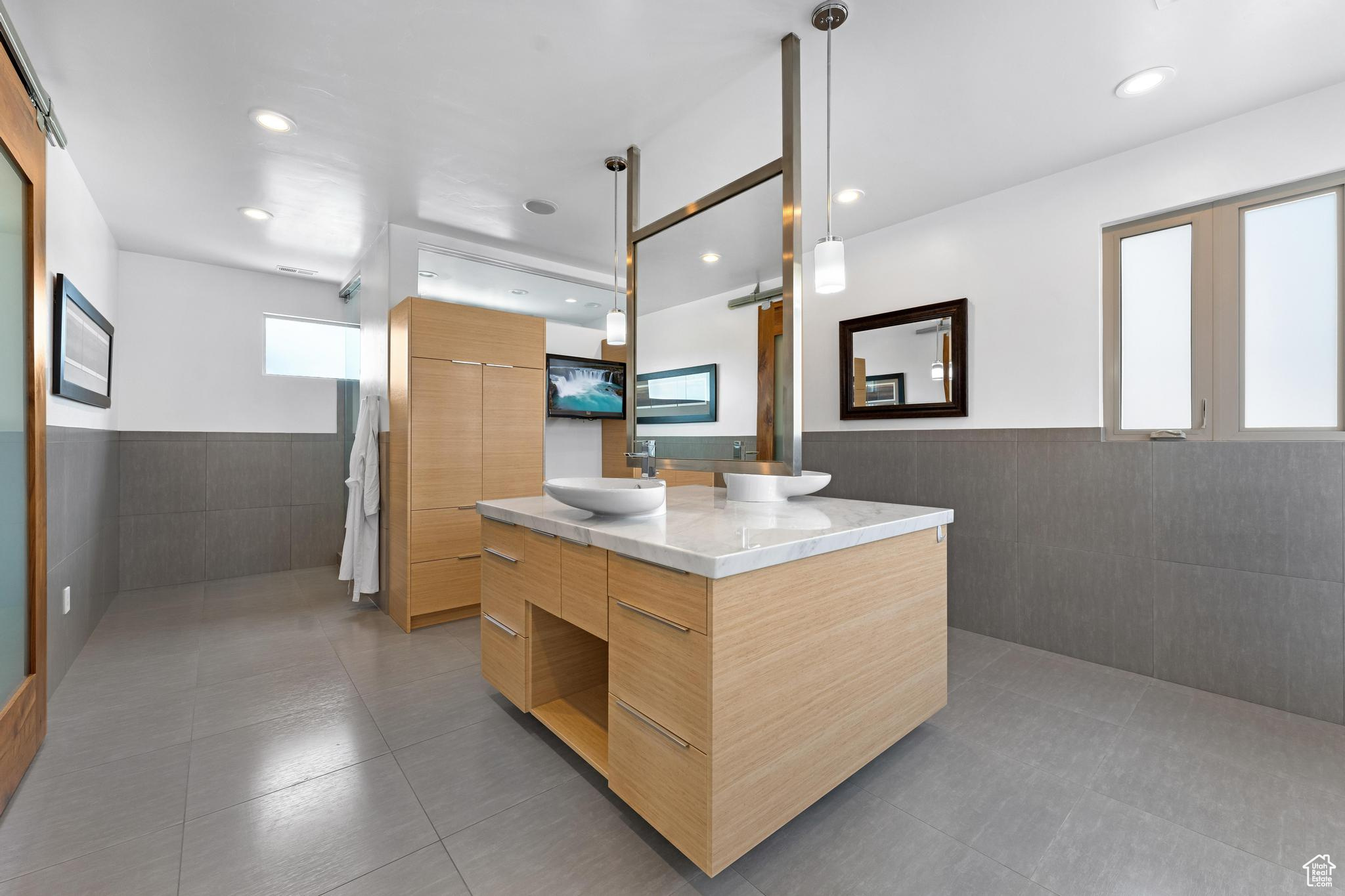 Kitchen featuring a kitchen island, light tile flooring, sink, tile walls, and decorative light fixtures