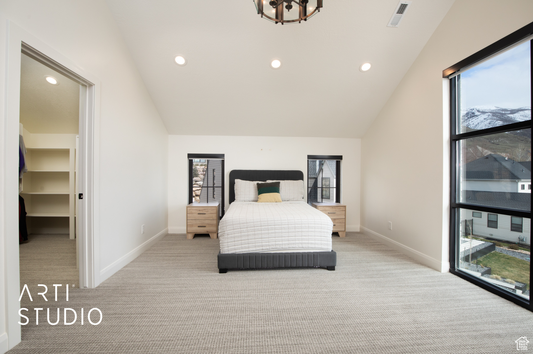Bedroom featuring a spacious closet, lofted ceiling, an inviting chandelier, and light colored carpet