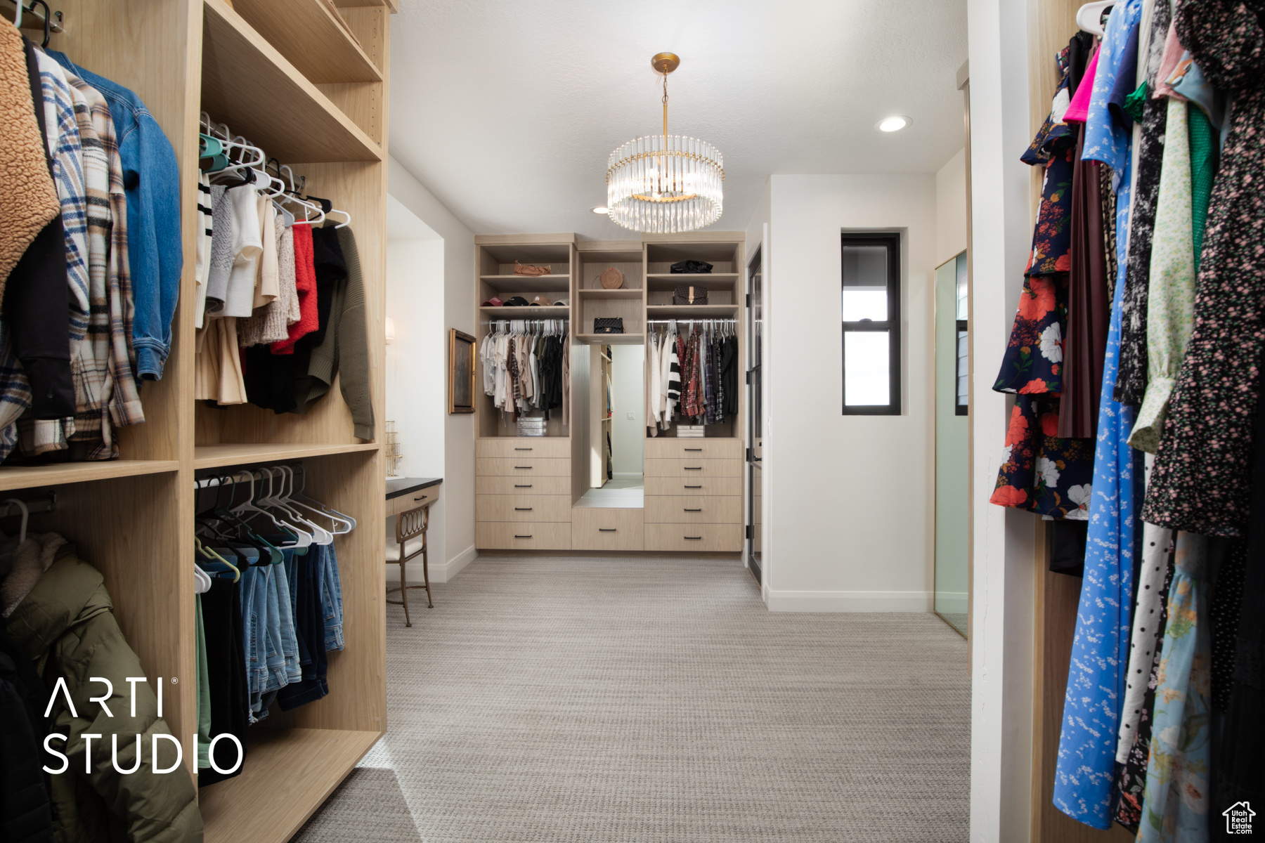 Spacious closet with light colored carpet and a chandelier