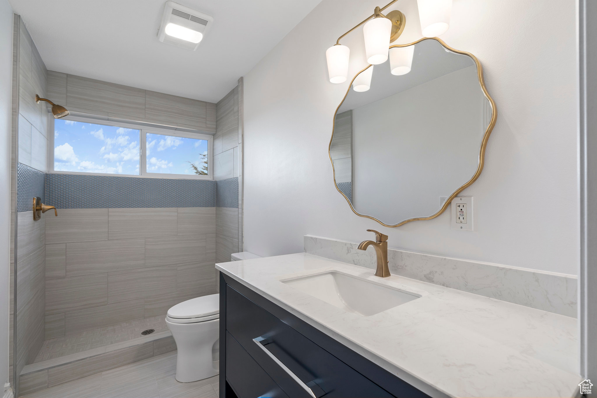 Basement bathroom with a tile shower, toilet, and vanity with extensive cabinet space
