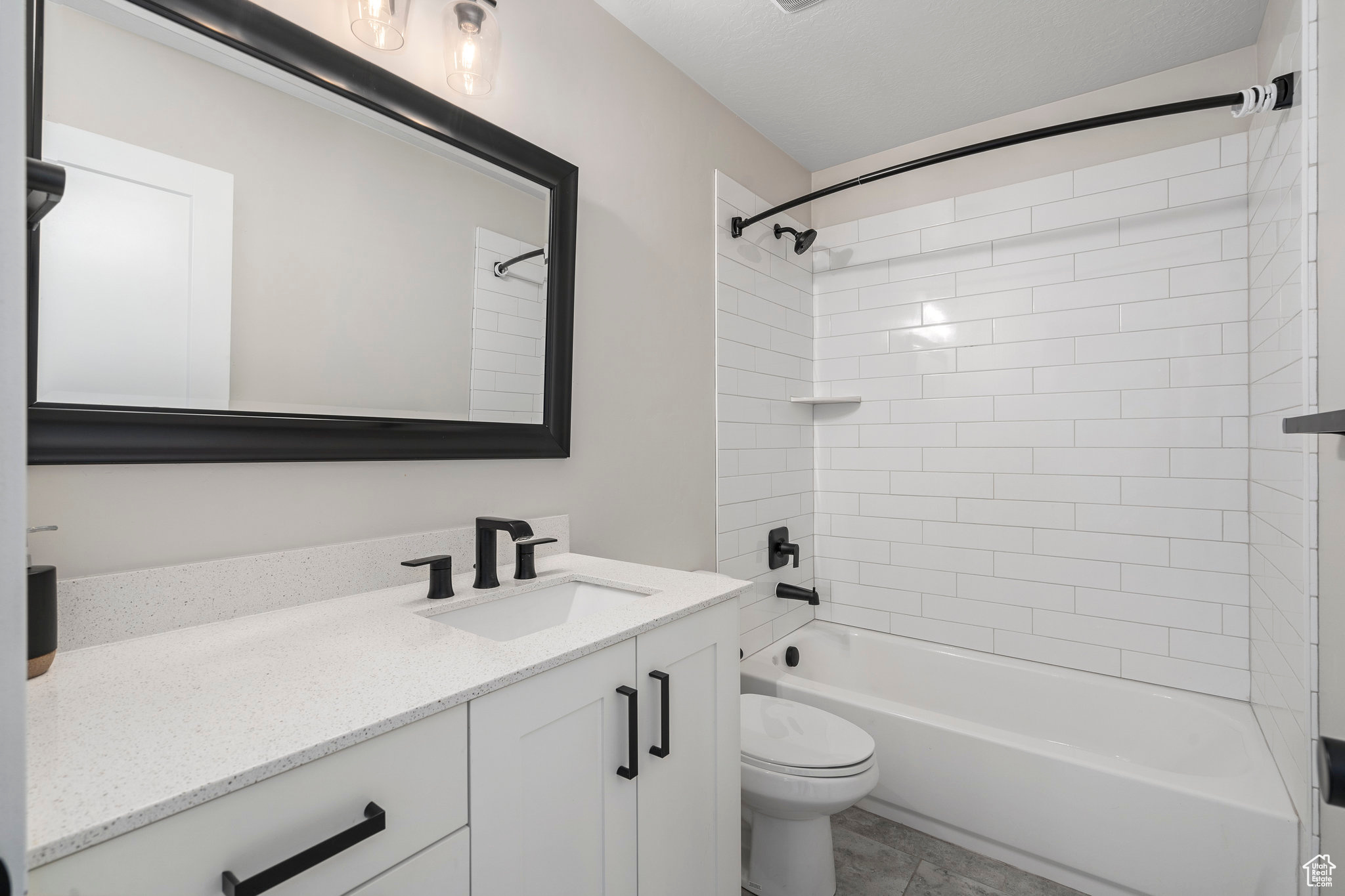 Full bathroom with tiled shower / bath, tile floors, toilet, and vanity