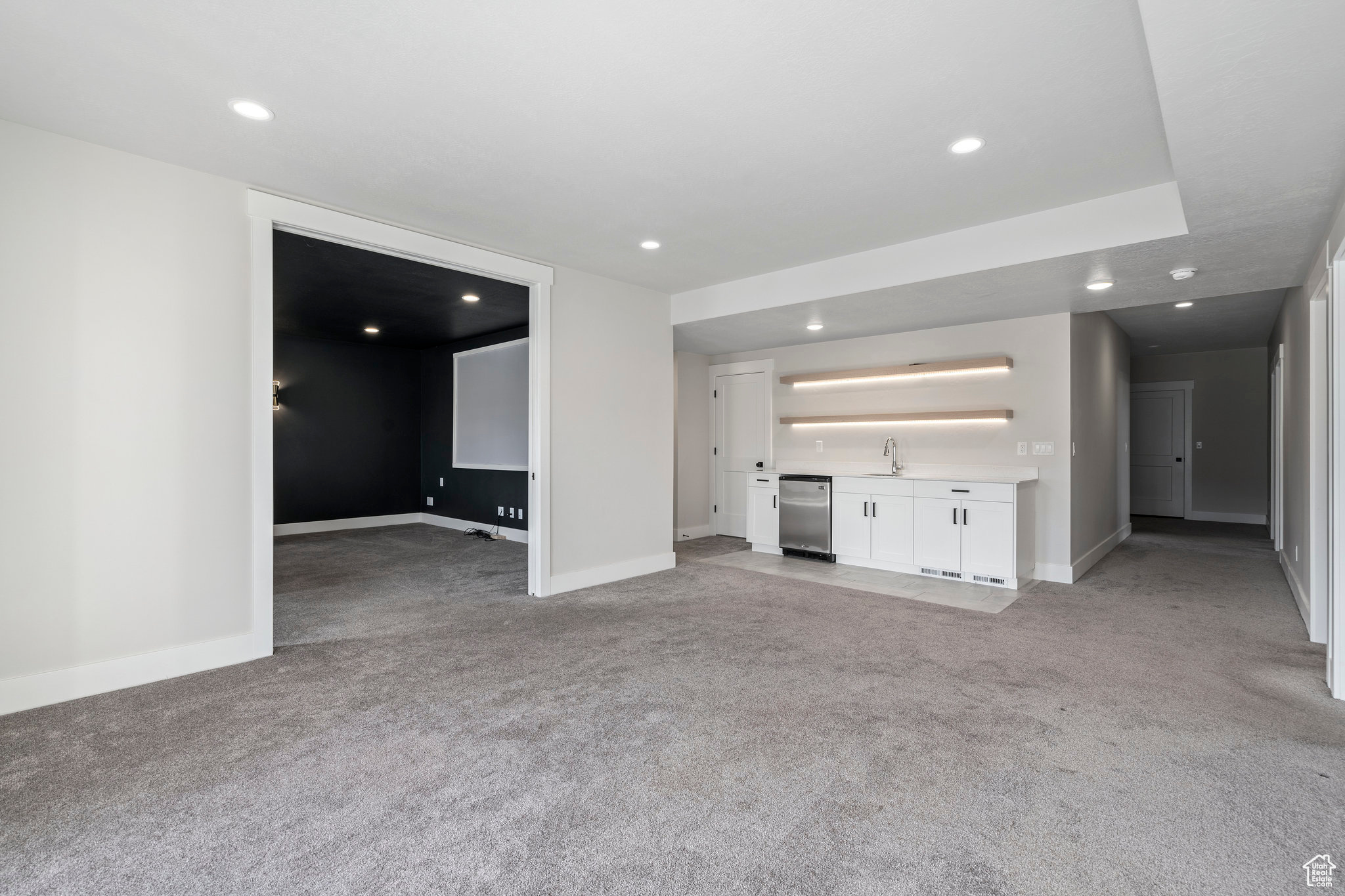 Unfurnished living room featuring sink and light colored carpet