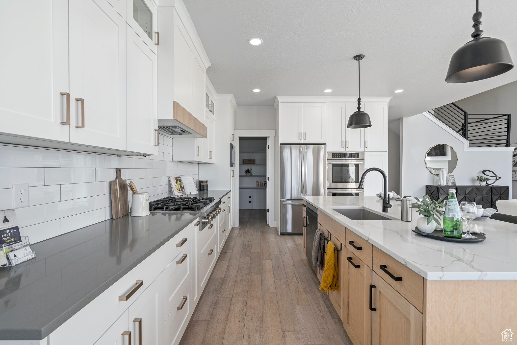 Kitchen with sink, light stone countertops, backsplash, light hardwood / wood-style floors, and white cabinetry