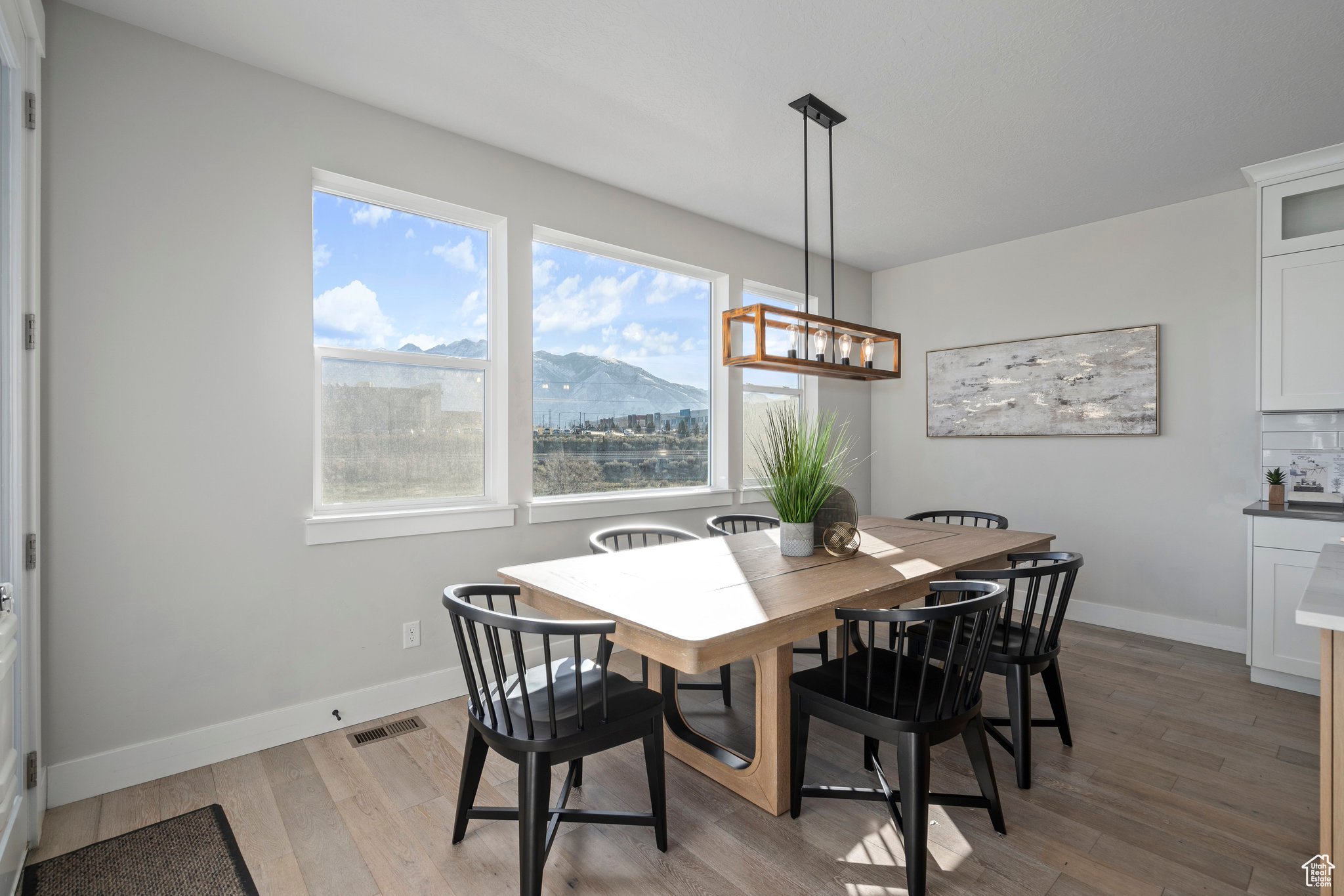 Dining space with a wealth of natural light, an inviting chandelier, light wood-type flooring, and a mountain view