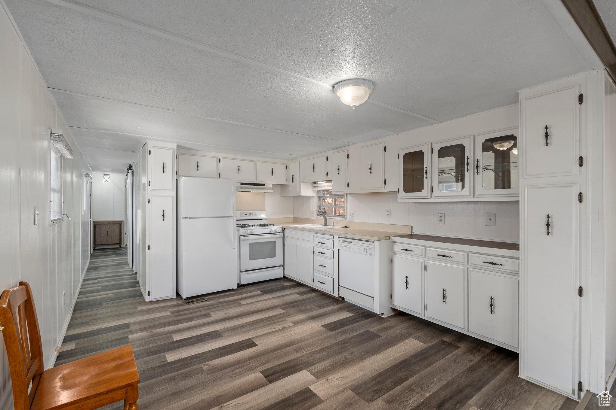 Kitchen with white cabinets, white appliances, and dark wood-type flooring