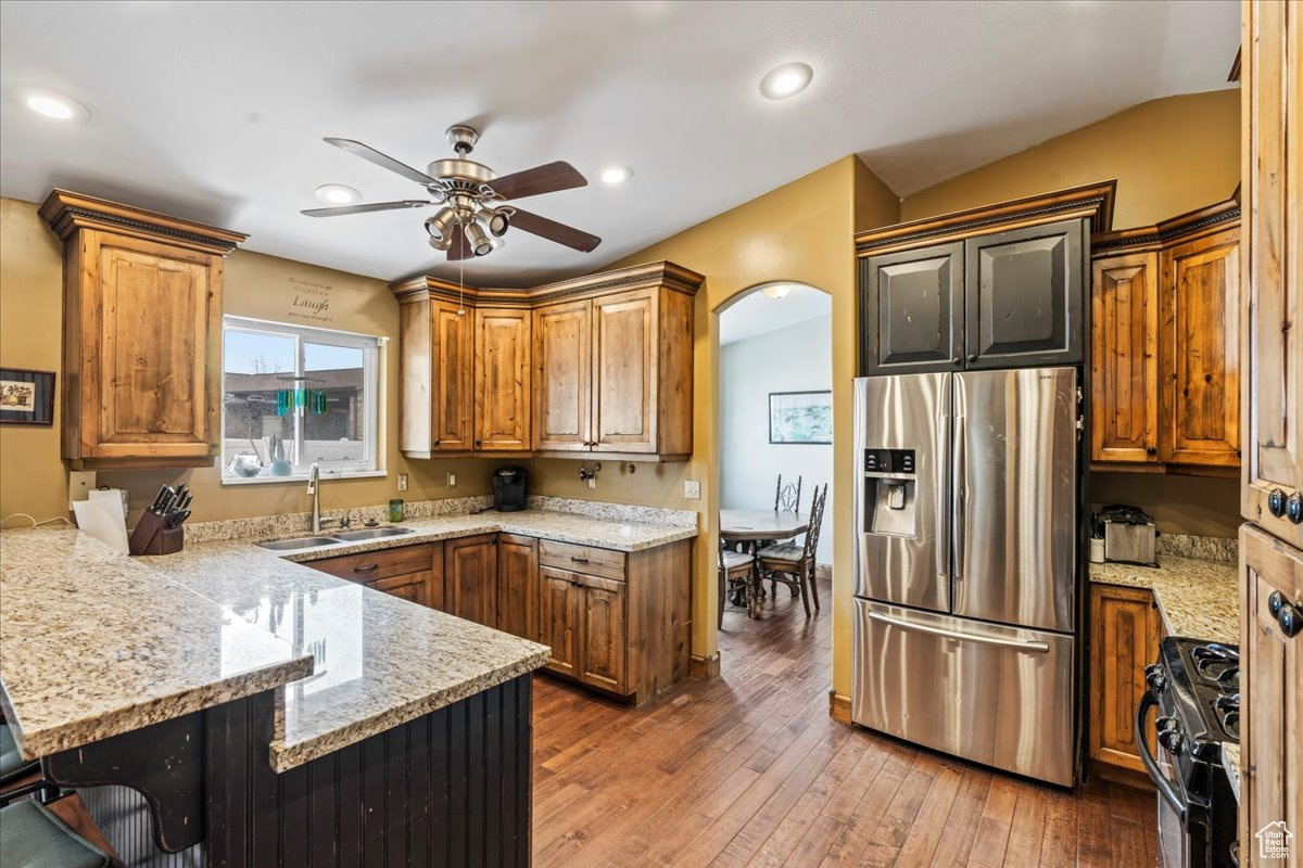 Kitchen featuring ceiling fan, dark hardwood / wood-style flooring, sink, black range, and stainless steel fridge