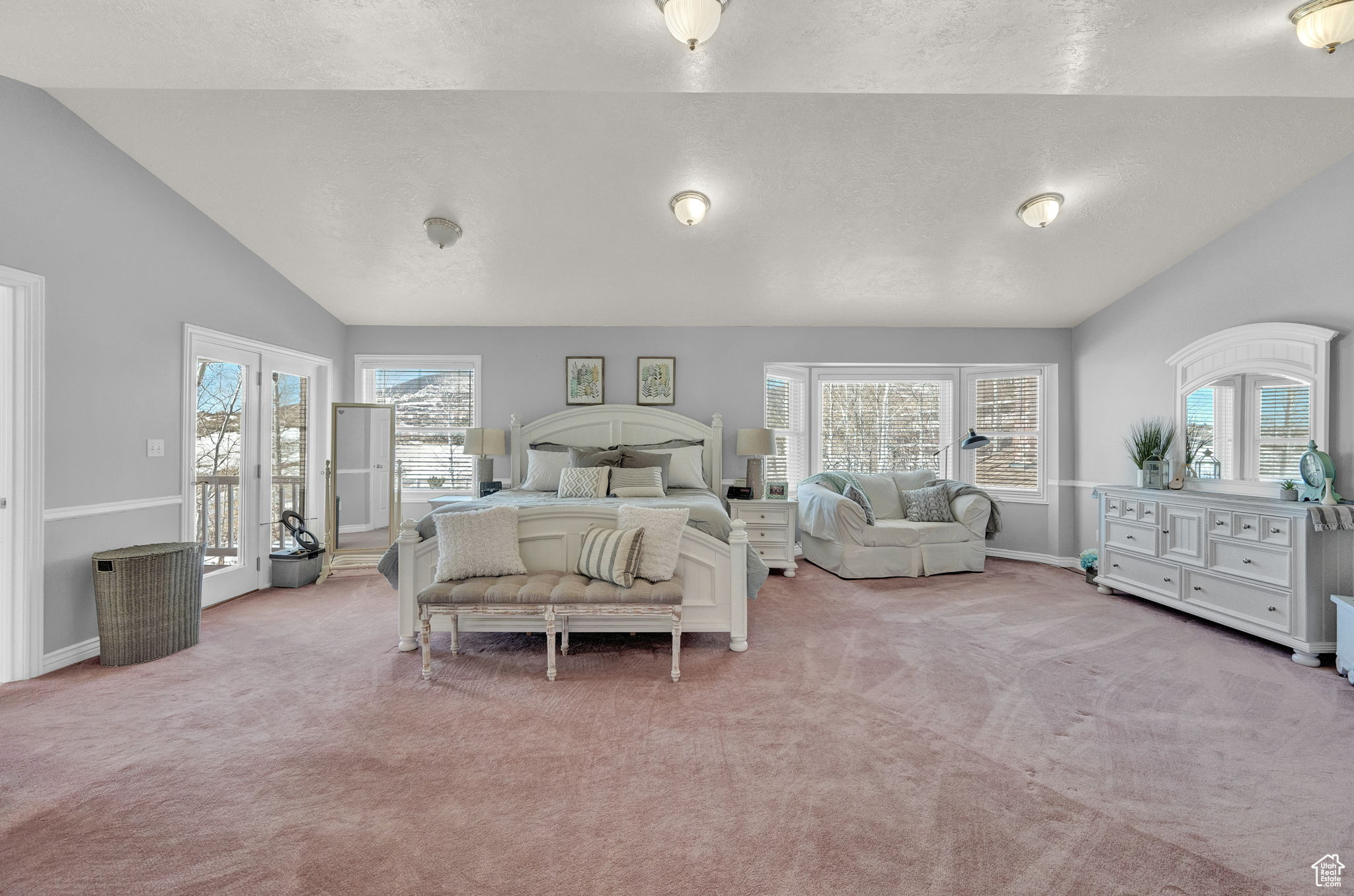 Carpeted bedroom with lofted ceiling, multiple windows, and french doors