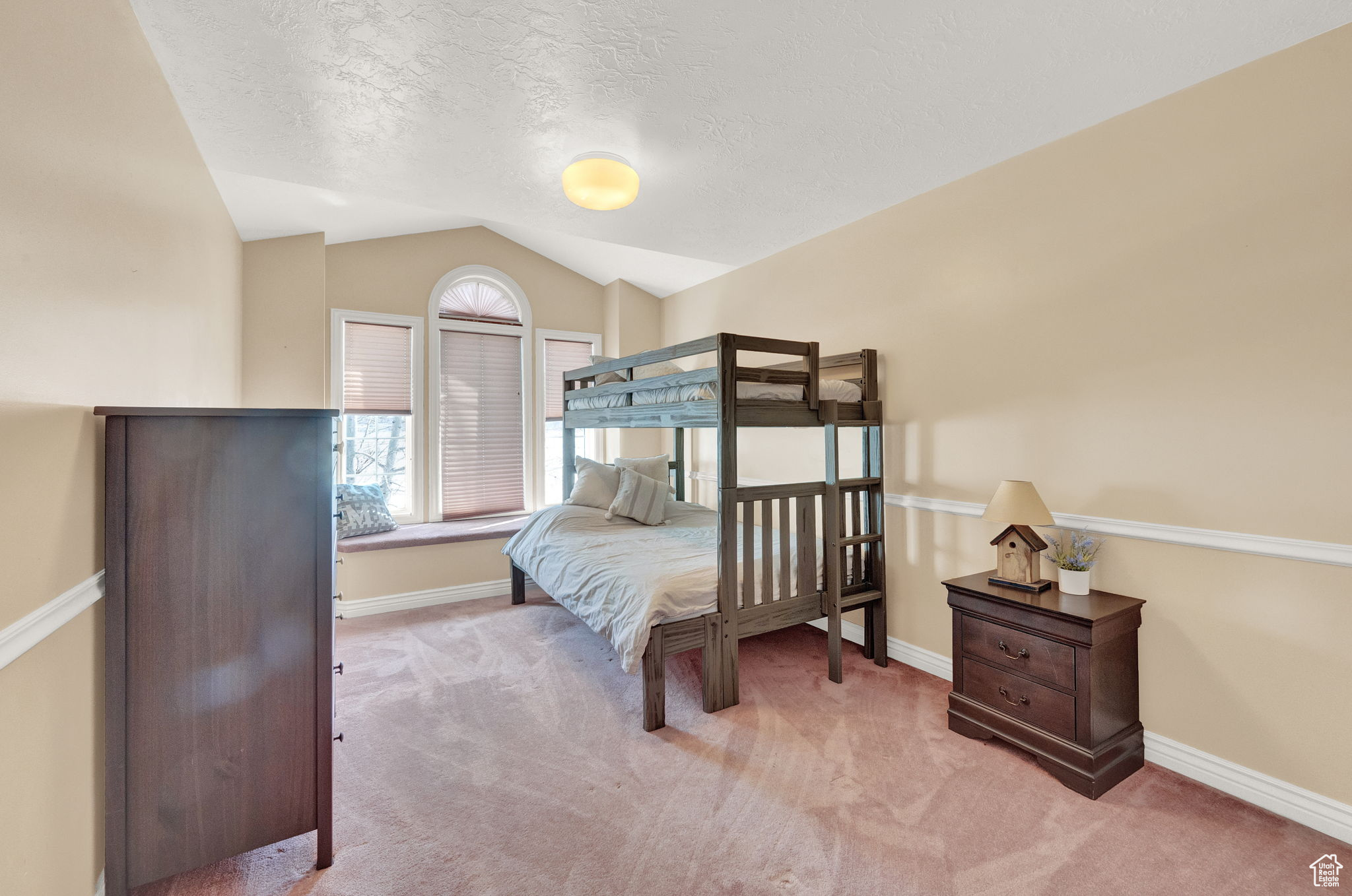 Bedroom with carpet floors, a textured ceiling, and vaulted ceiling