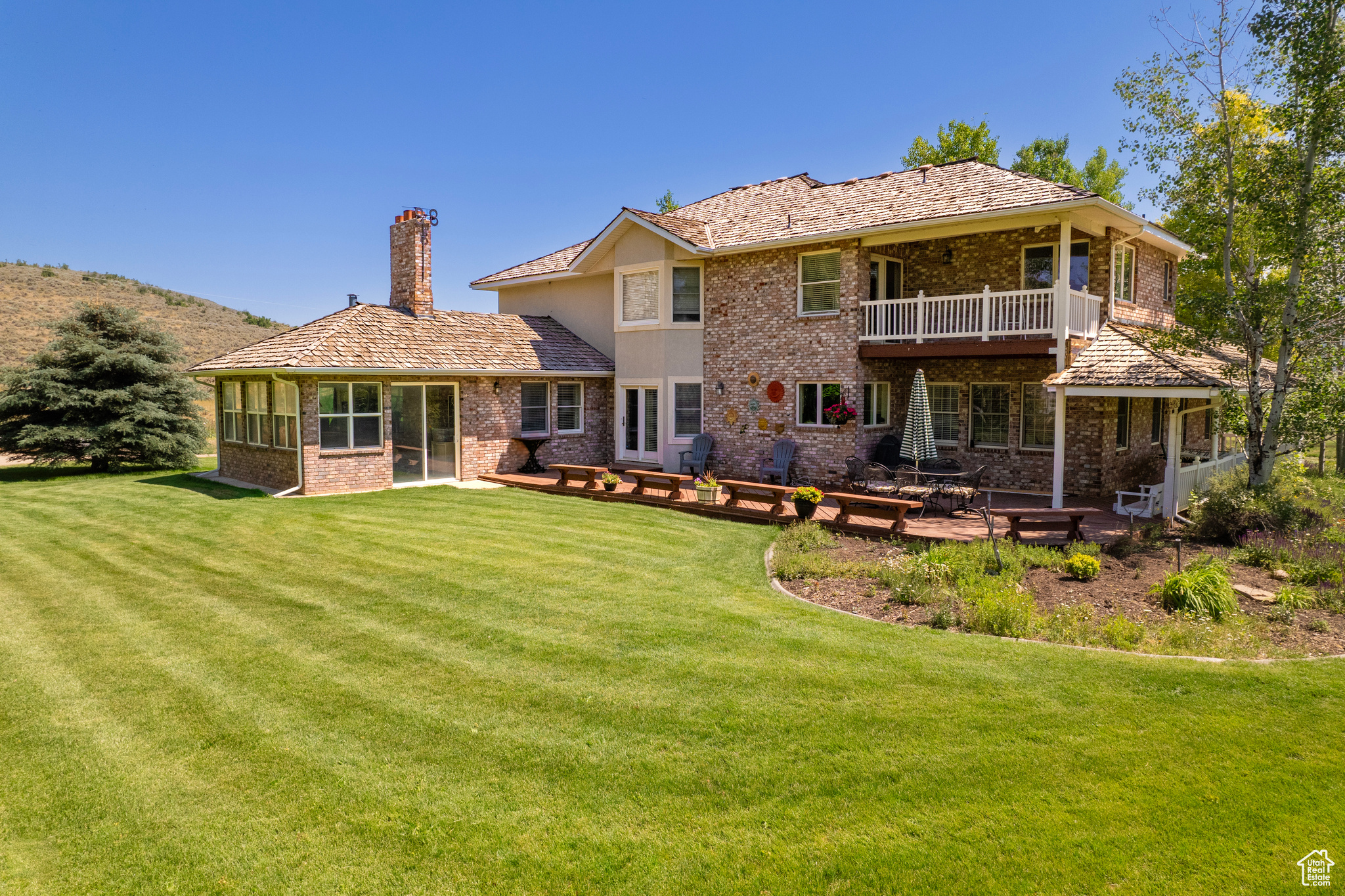 Back of house featuring a balcony and a lawn