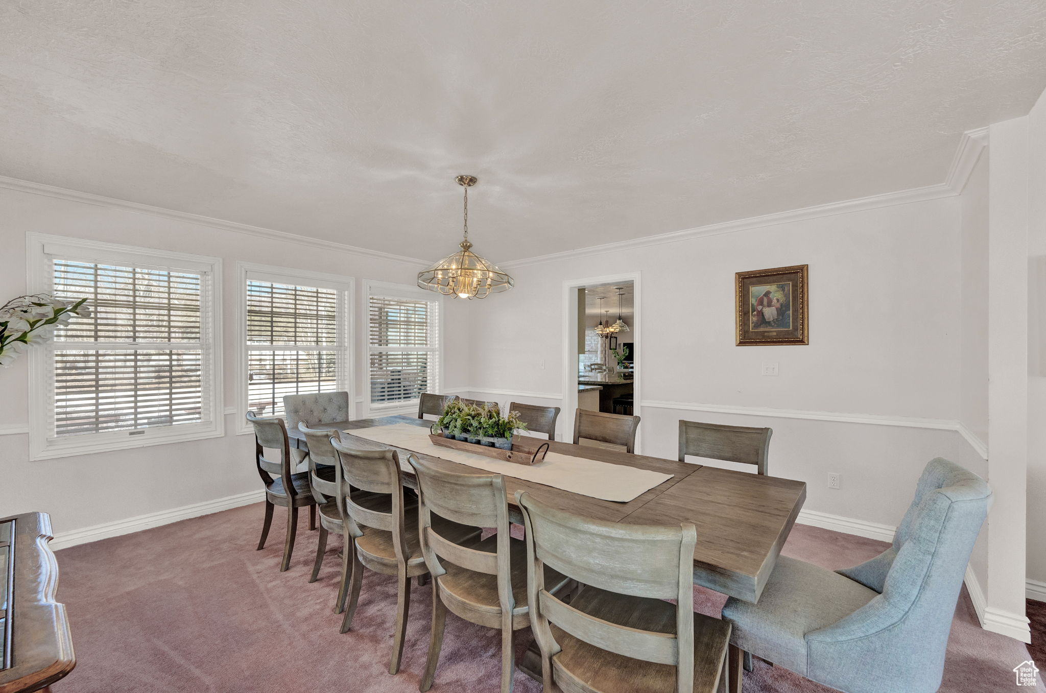 Dining area featuring dark colored carpet, a chandelier, and ornamental molding