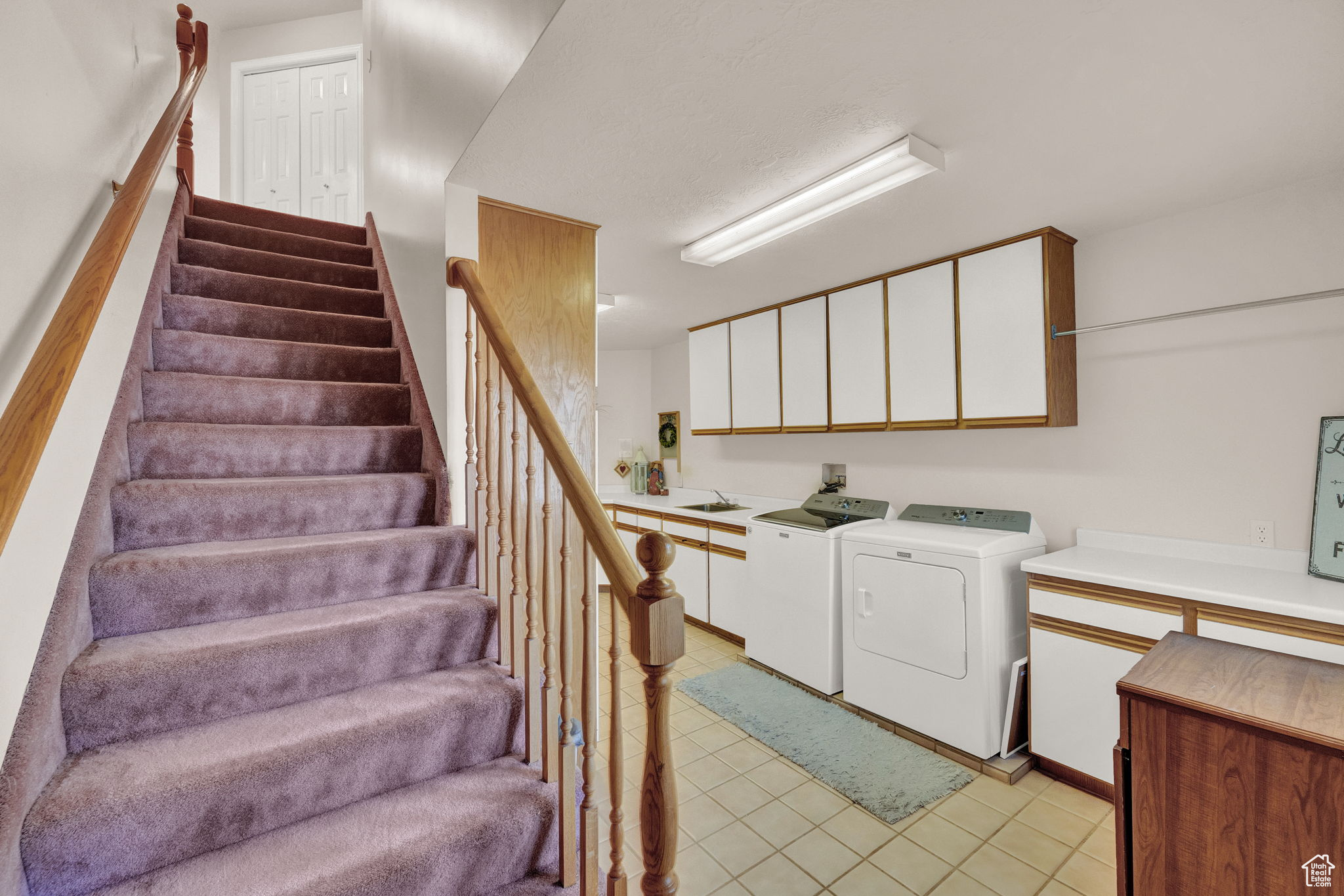 Washroom featuring cabinets, washer and dryer, sink, and light tile patterned floors