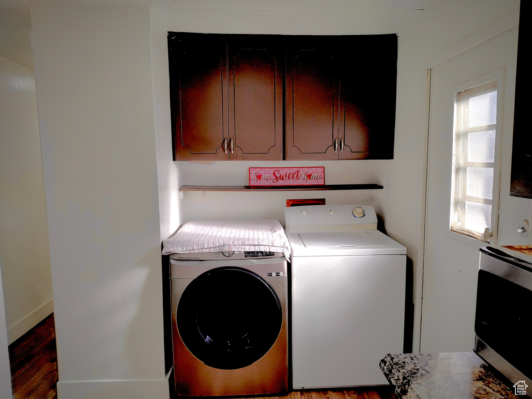 Laundry area featuring washing machine and dryer, cabinets, and light hardwood / wood-style flooring