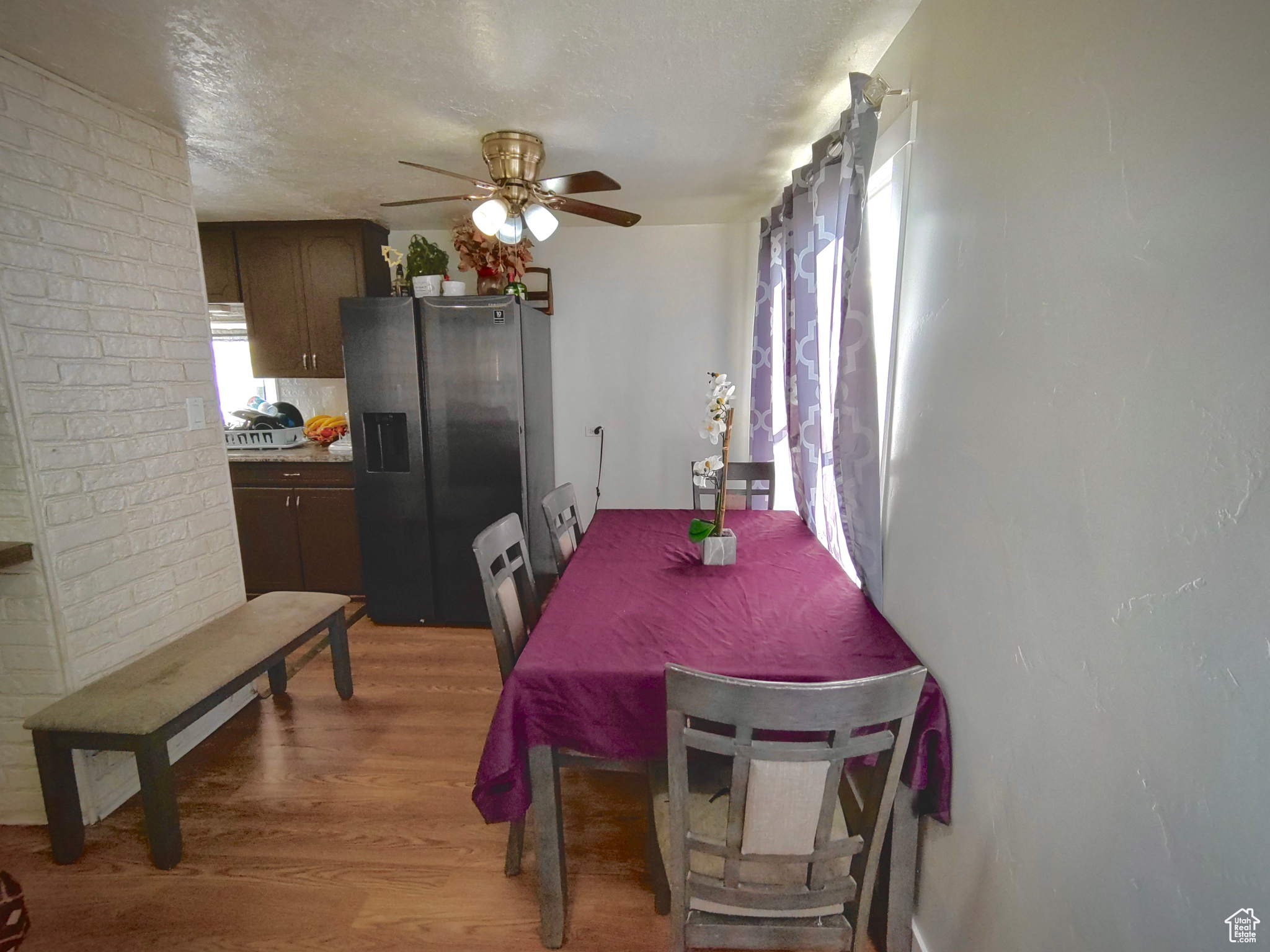 Dining space featuring brick wall, ceiling fan, and hardwood / wood-style floors