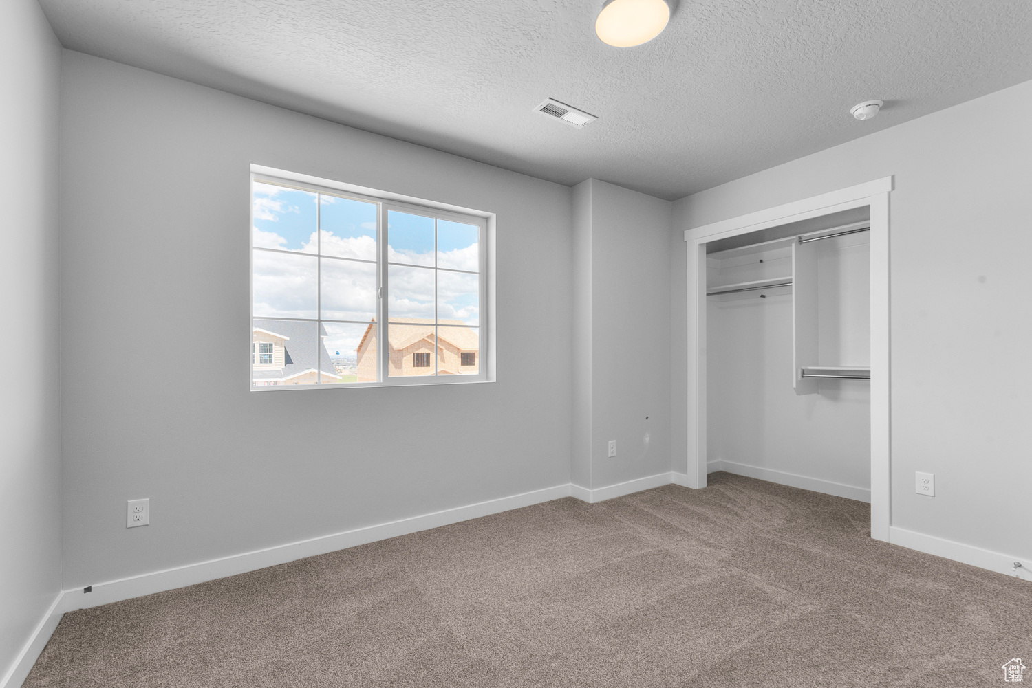 Unfurnished bedroom with carpet, a closet, and a textured ceiling