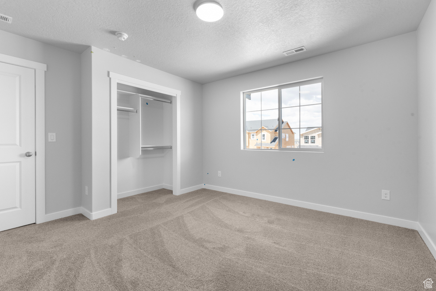 Unfurnished bedroom featuring light carpet, a textured ceiling, and a closet