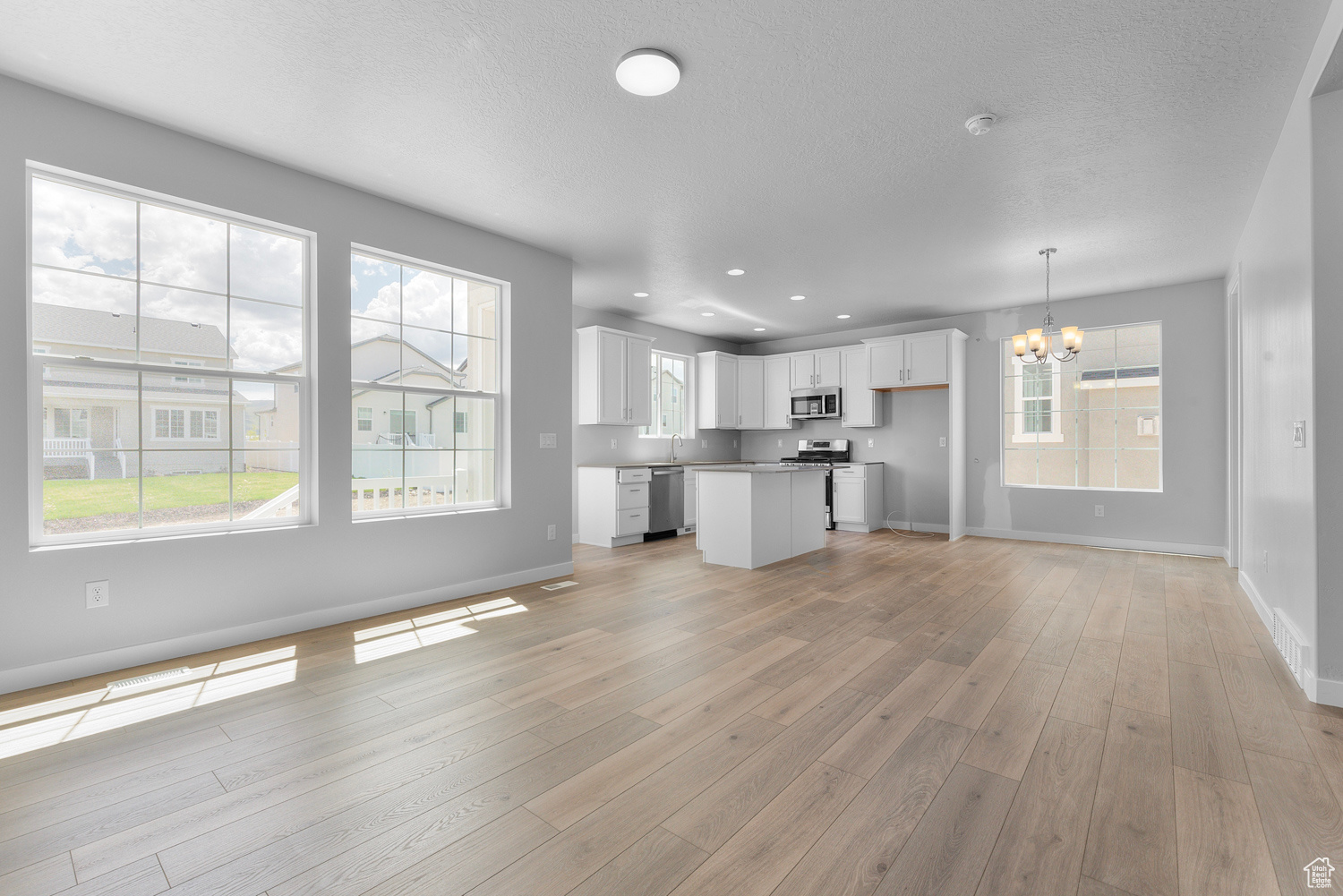 Unfurnished living room with a chandelier and light hardwood / wood-style floors